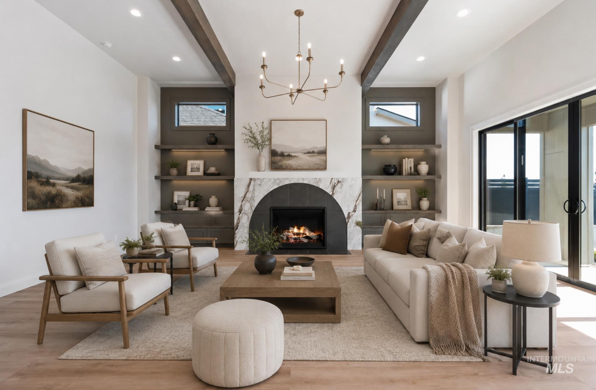 Spacious living area featuring a fireplace with a white stone surround, light wood-finish flooring, exposed ceiling beams, built-in shelving with recessed lighting, and a multi-pane sliding glass door