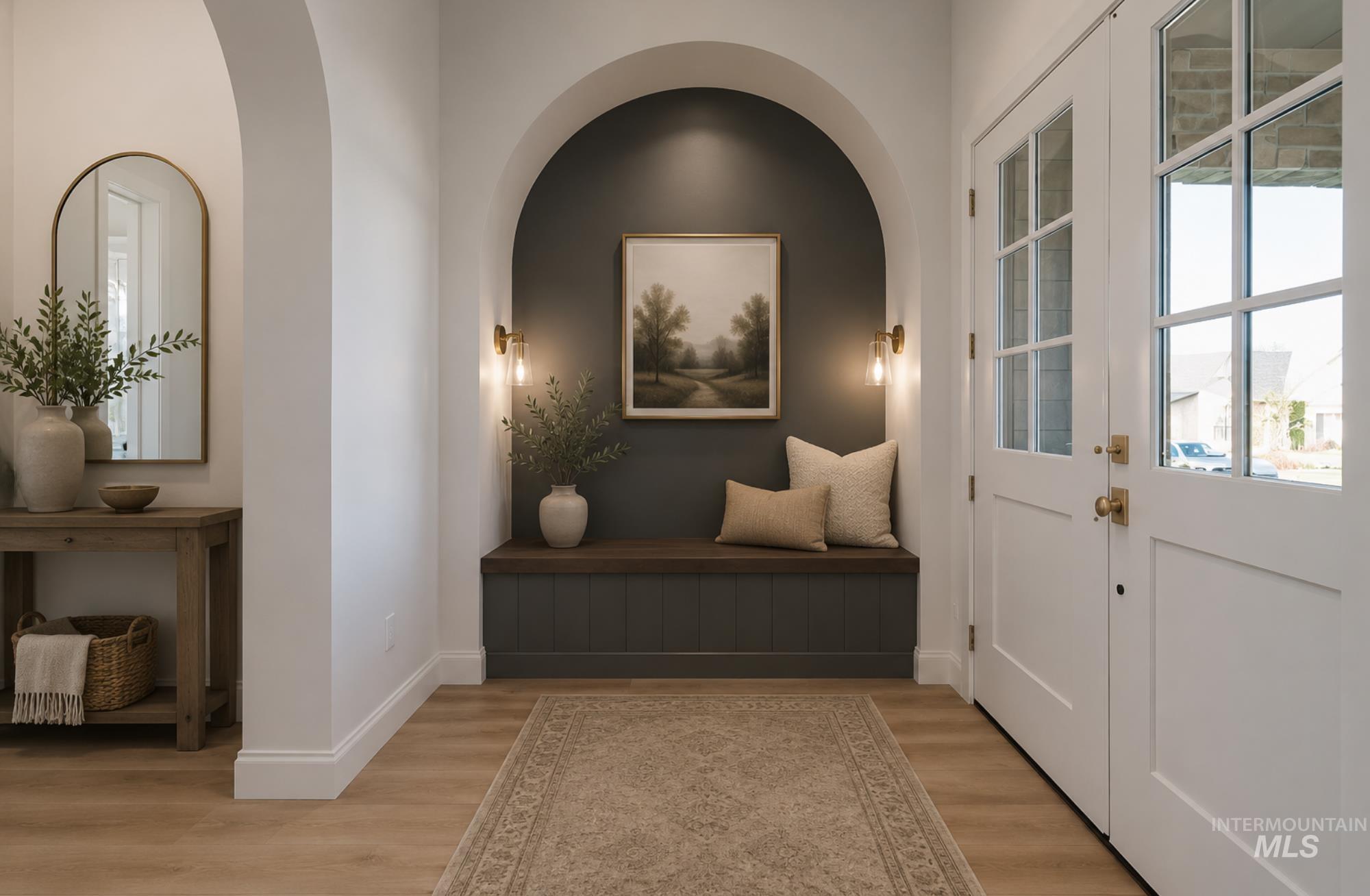 Entryway featuring light wood-finish flooring, white paneled doors with grid-patterned windows, and brass hardware