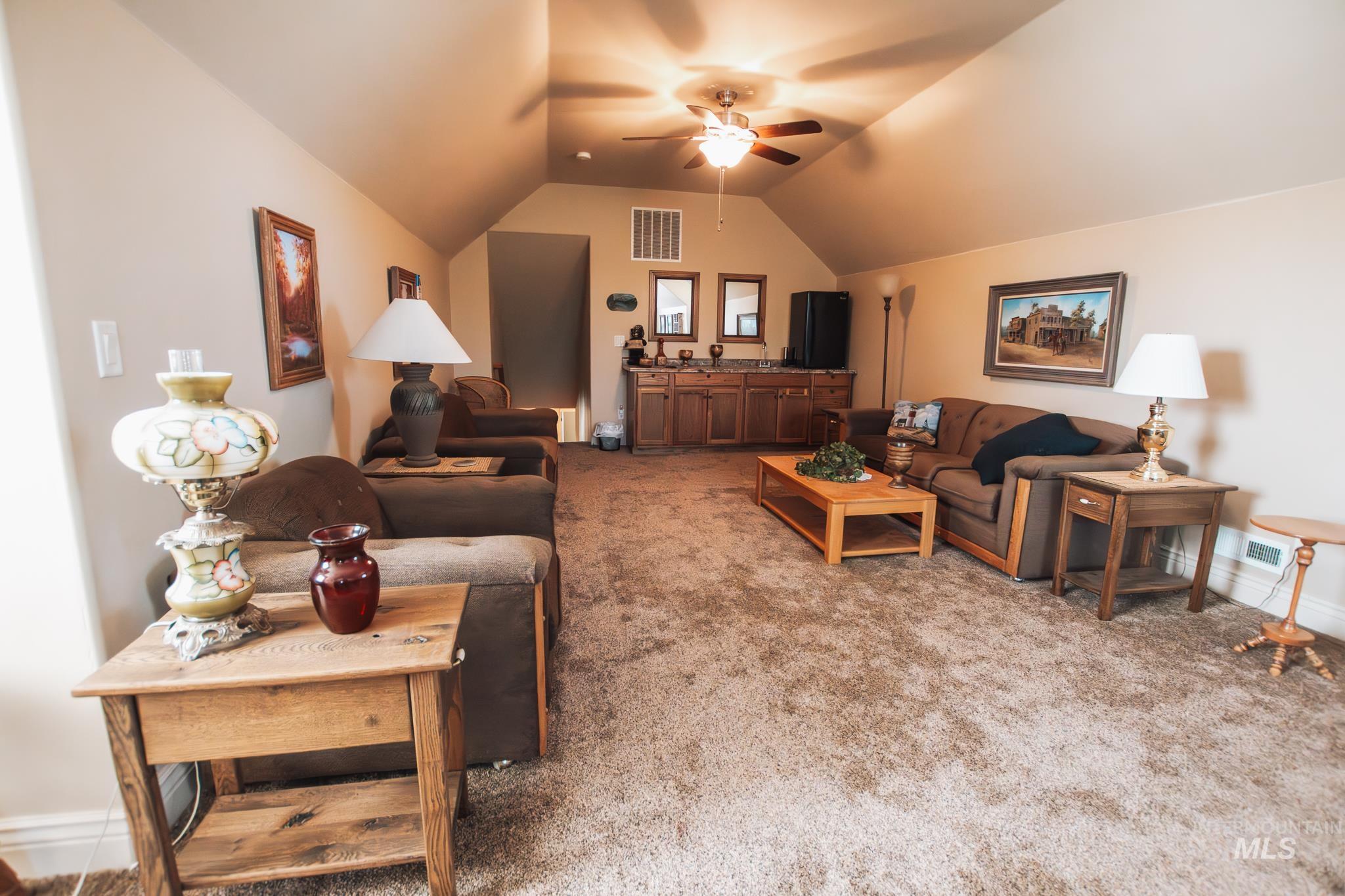 Bonus room featuring  wet bar, vaulted ceiling, carpet floors, and ceiling fan