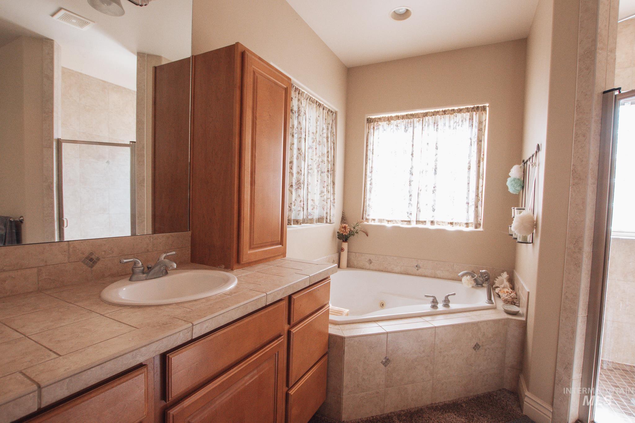Full bathroom featuring vanity, a jetted tub, and a stall shower
