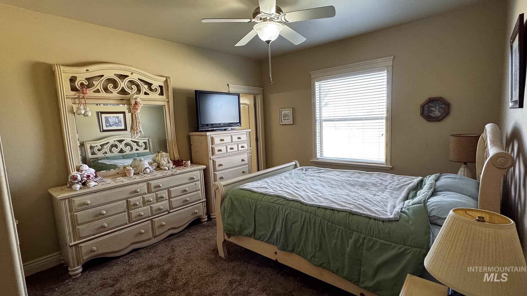 Bedroom with dark colored carpet and a ceiling fan