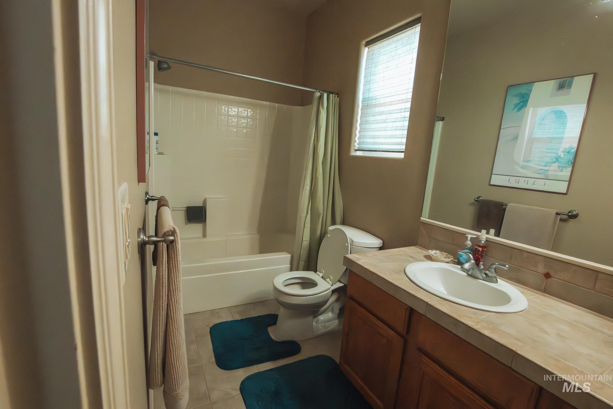 Full bath with vanity, shower / bath combo with shower curtain, and tile patterned flooring