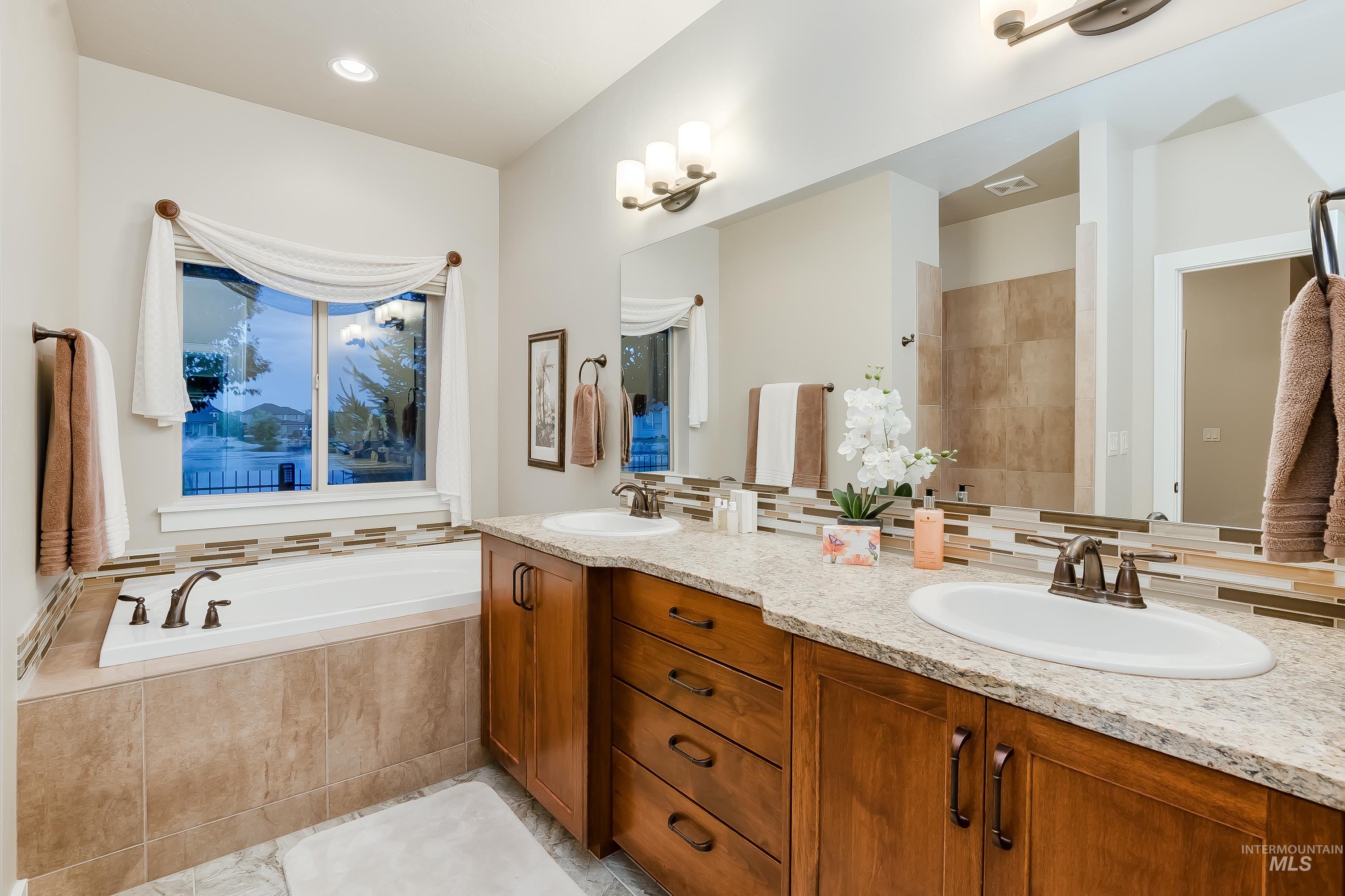 Full bathroom featuring a bath, double vanity, backsplash, walk in shower, and recessed lighting