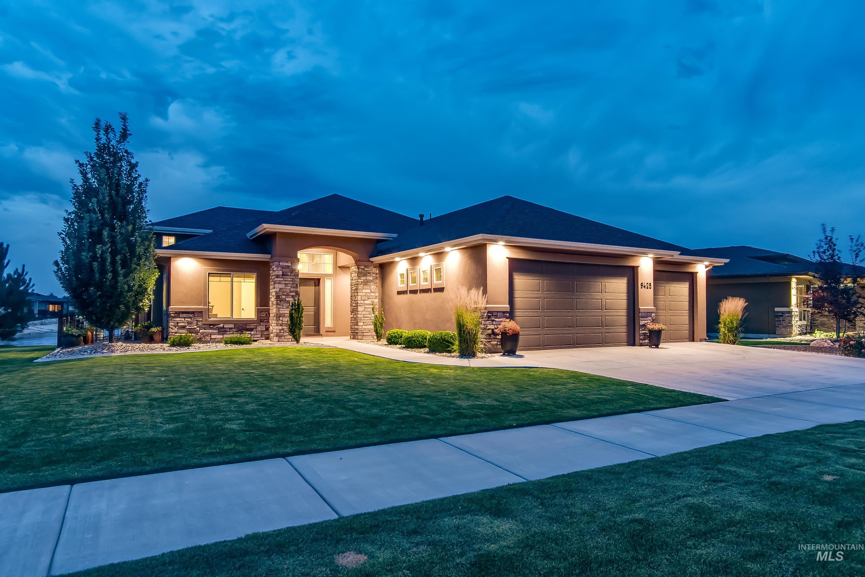 Prairie-style home with stone siding, an attached garage, driveway, stucco siding, and a front lawn