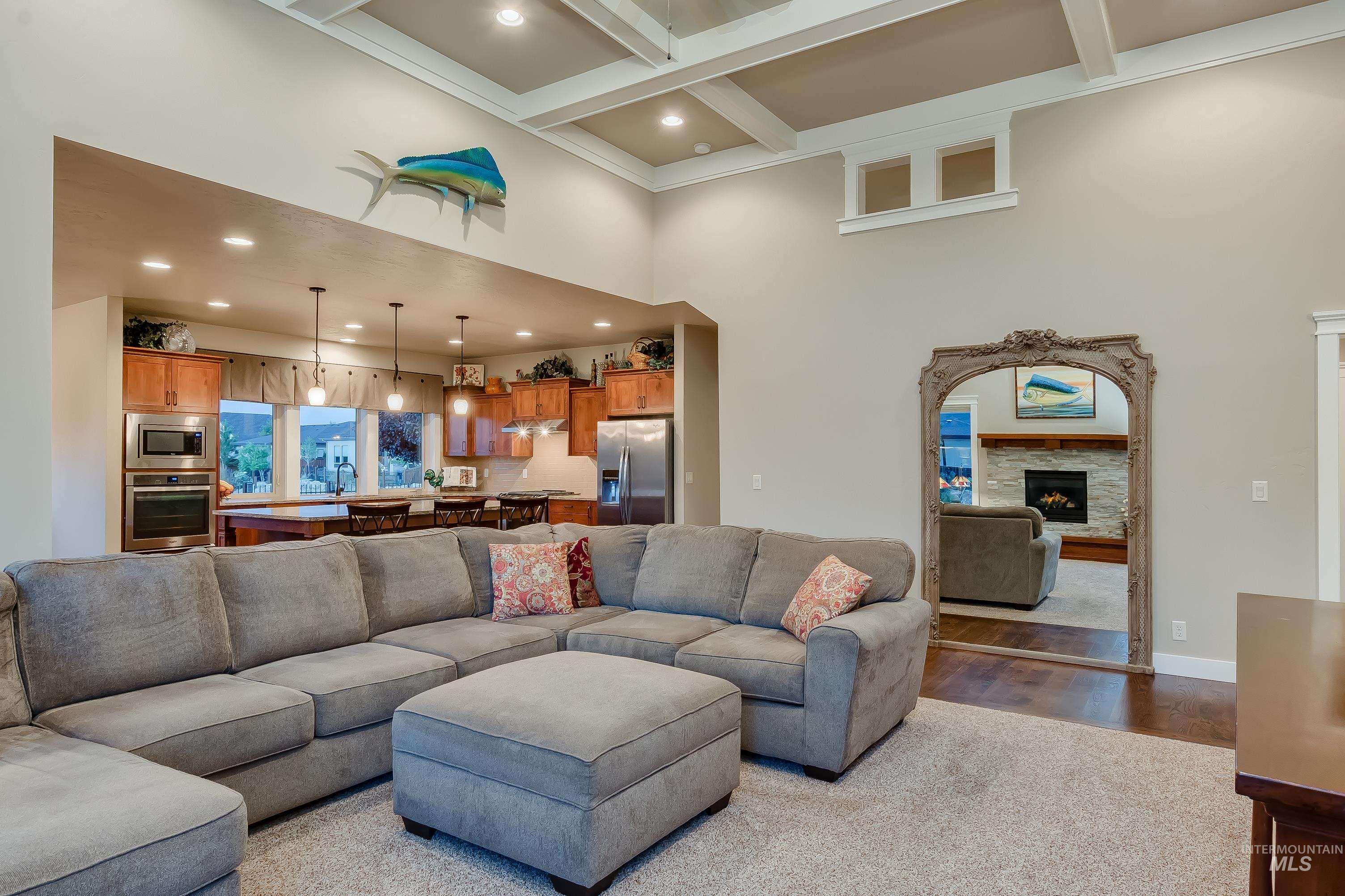 Living area with recessed lighting, light wood-style floors, beamed ceiling, a high ceiling, and coffered ceiling