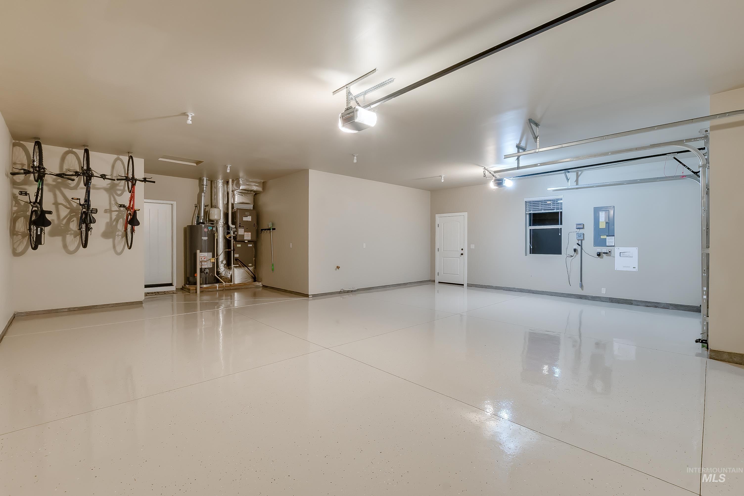 Garage with water heater, electric panel, heating unit, and a garage door opener