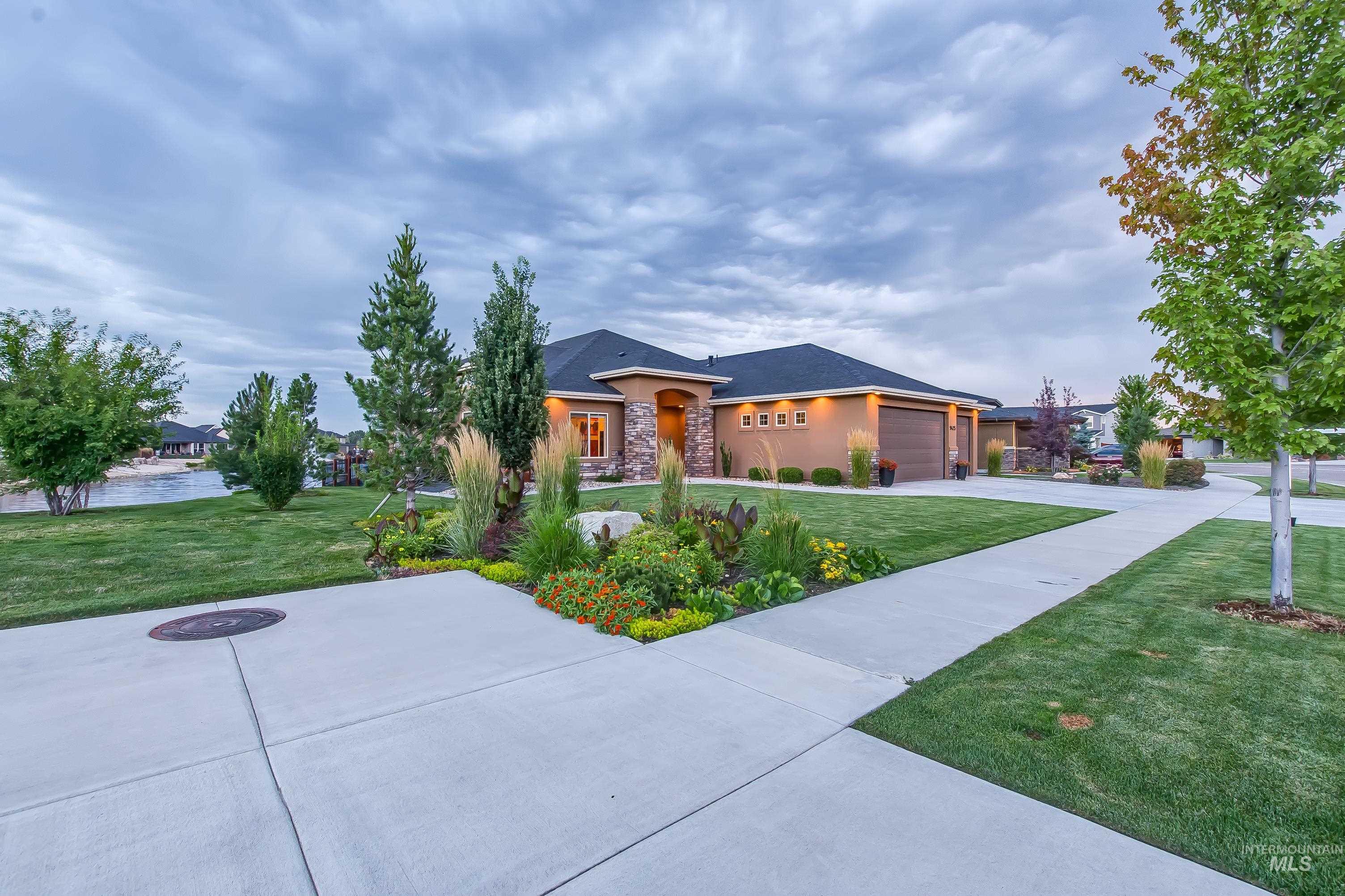 Prairie-style house featuring a front lawn, stone siding, driveway, and a garage