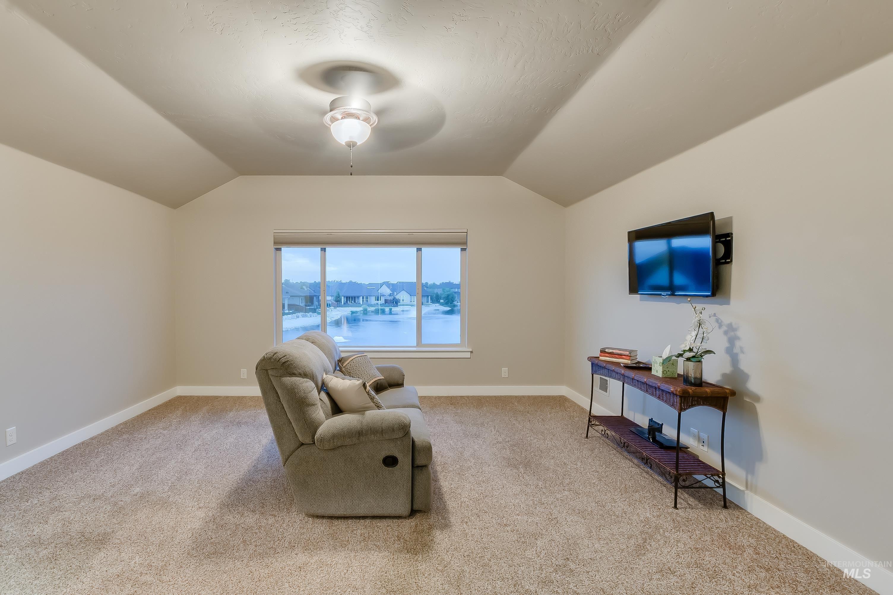 Sitting room featuring vaulted ceiling and light carpet