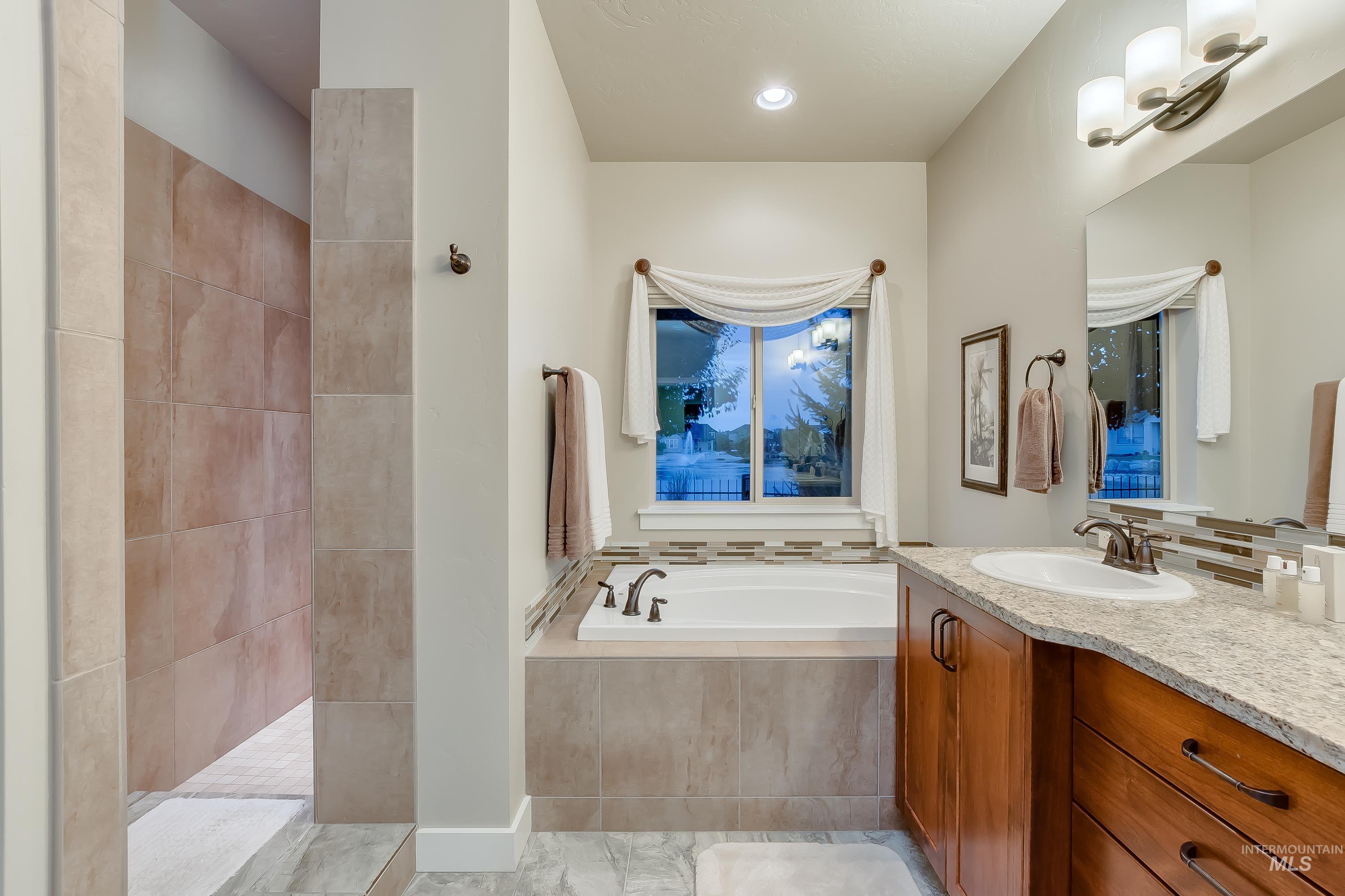 Full bathroom featuring a bath, vanity, walk in shower, and recessed lighting