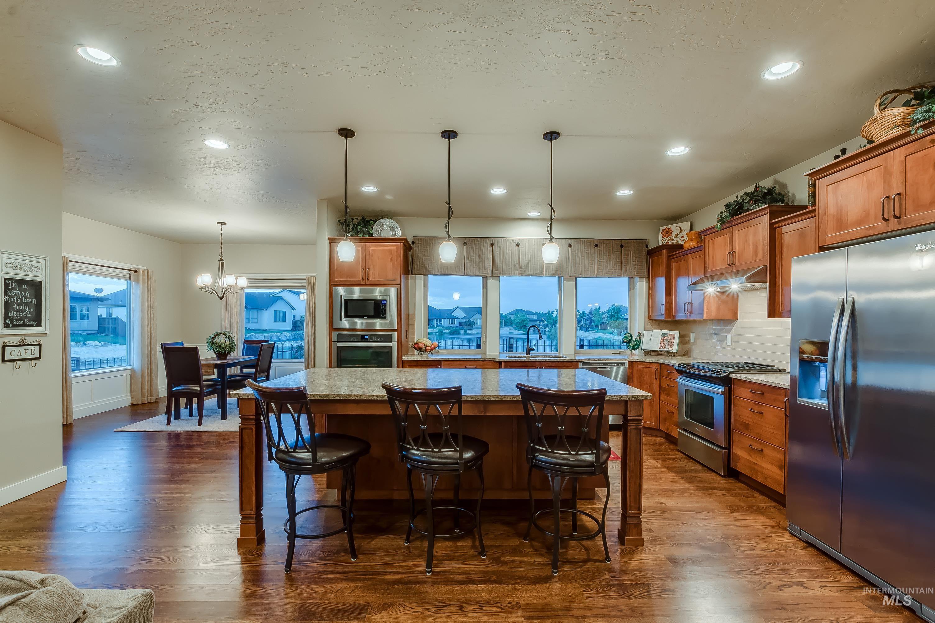 Kitchen featuring brown cabinetry, stainless steel appliances, a center island, pendant lighting, and a breakfast bar area