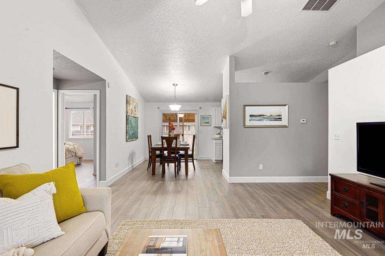 Living area featuring light wood finished floors, a textured ceiling, and a ceiling fan