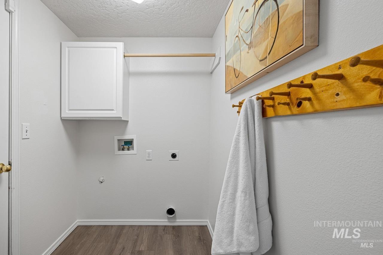Laundry area featuring hookup for a washing machine, electric dryer hookup, cabinet space, dark wood-style flooring, and a textured ceiling