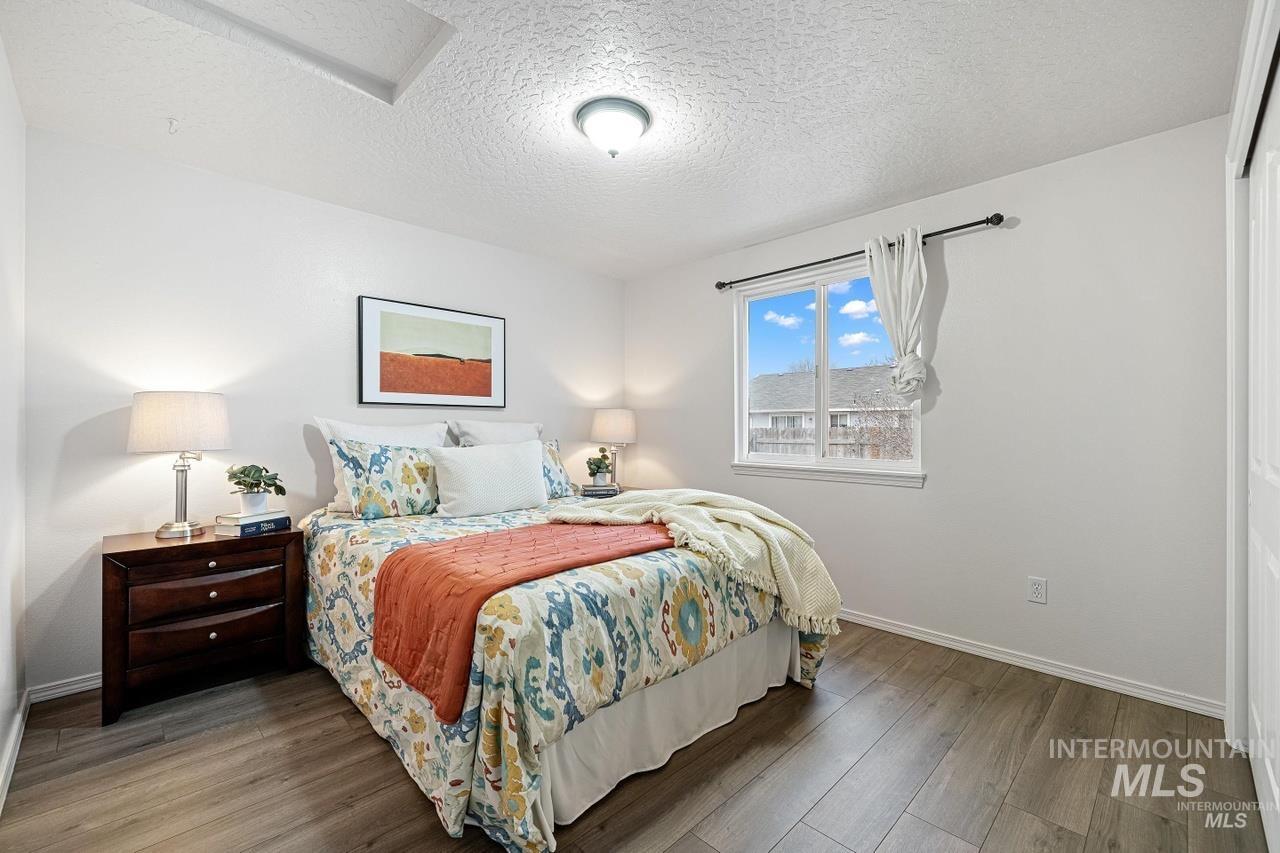 Bedroom with wood finished floors, a textured ceiling, and attic access