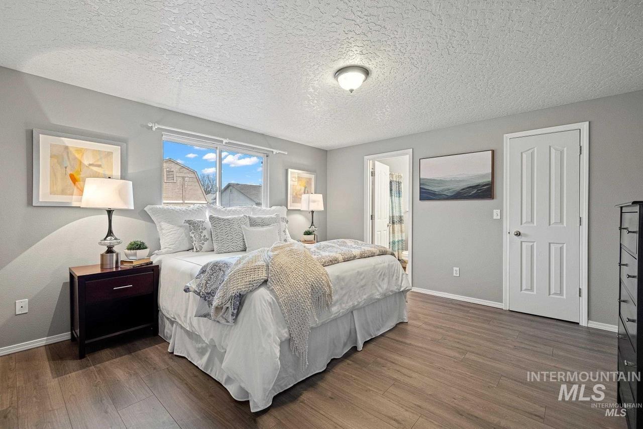 Bedroom with wood finished floors, a textured ceiling, and connected bathroom