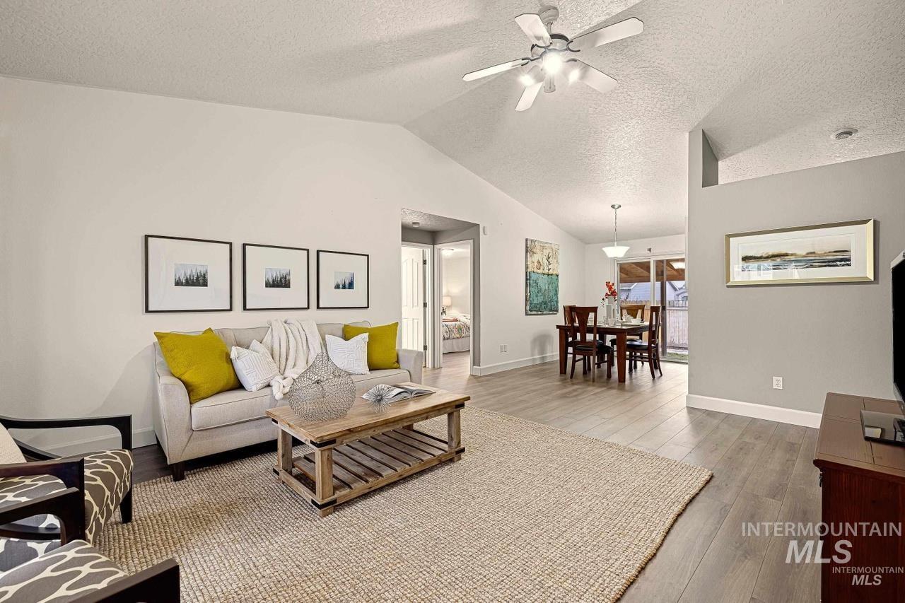 Living area featuring wood finished floors, ceiling fan, vaulted ceiling, and a textured ceiling