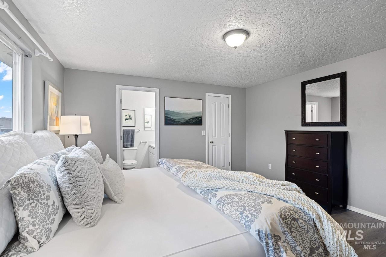 Bedroom featuring dark wood-style floors, a textured ceiling, and ensuite bathroom