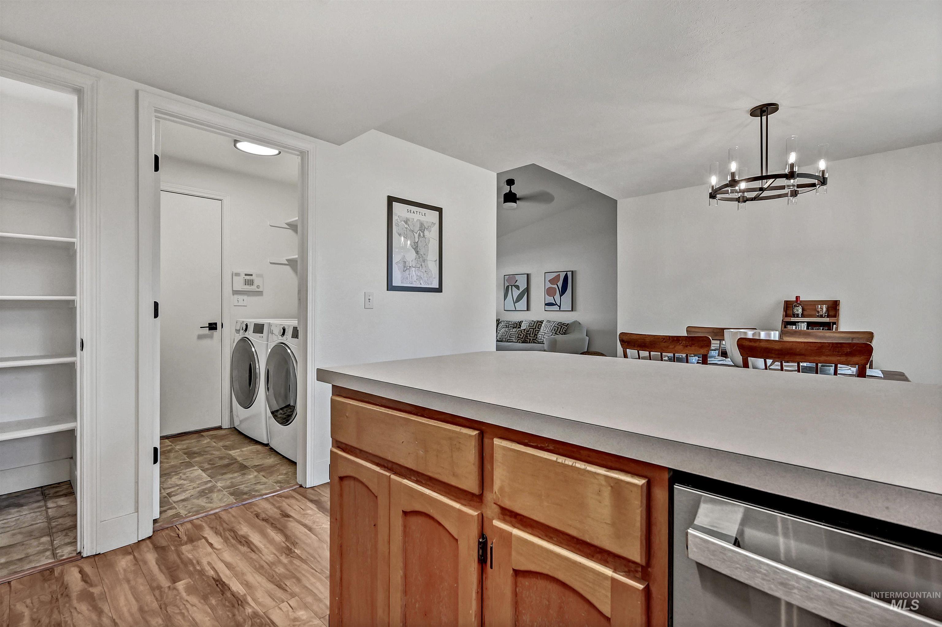 Kitchen with a peninsula, light countertops, light wood-style floors, stainless appliances, and a pantry