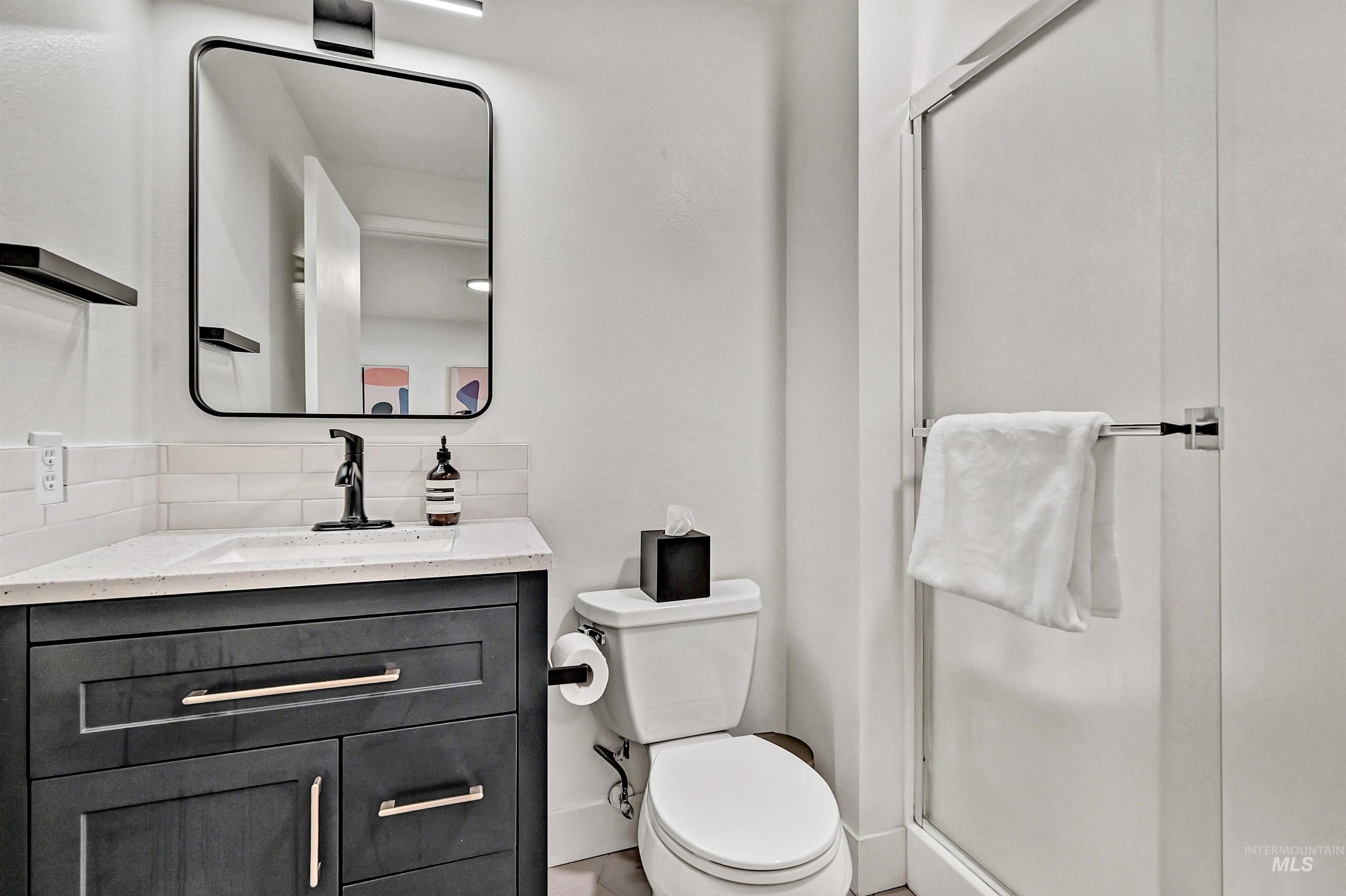 Ensuite bathroom featuring a shower stall and updated vanity