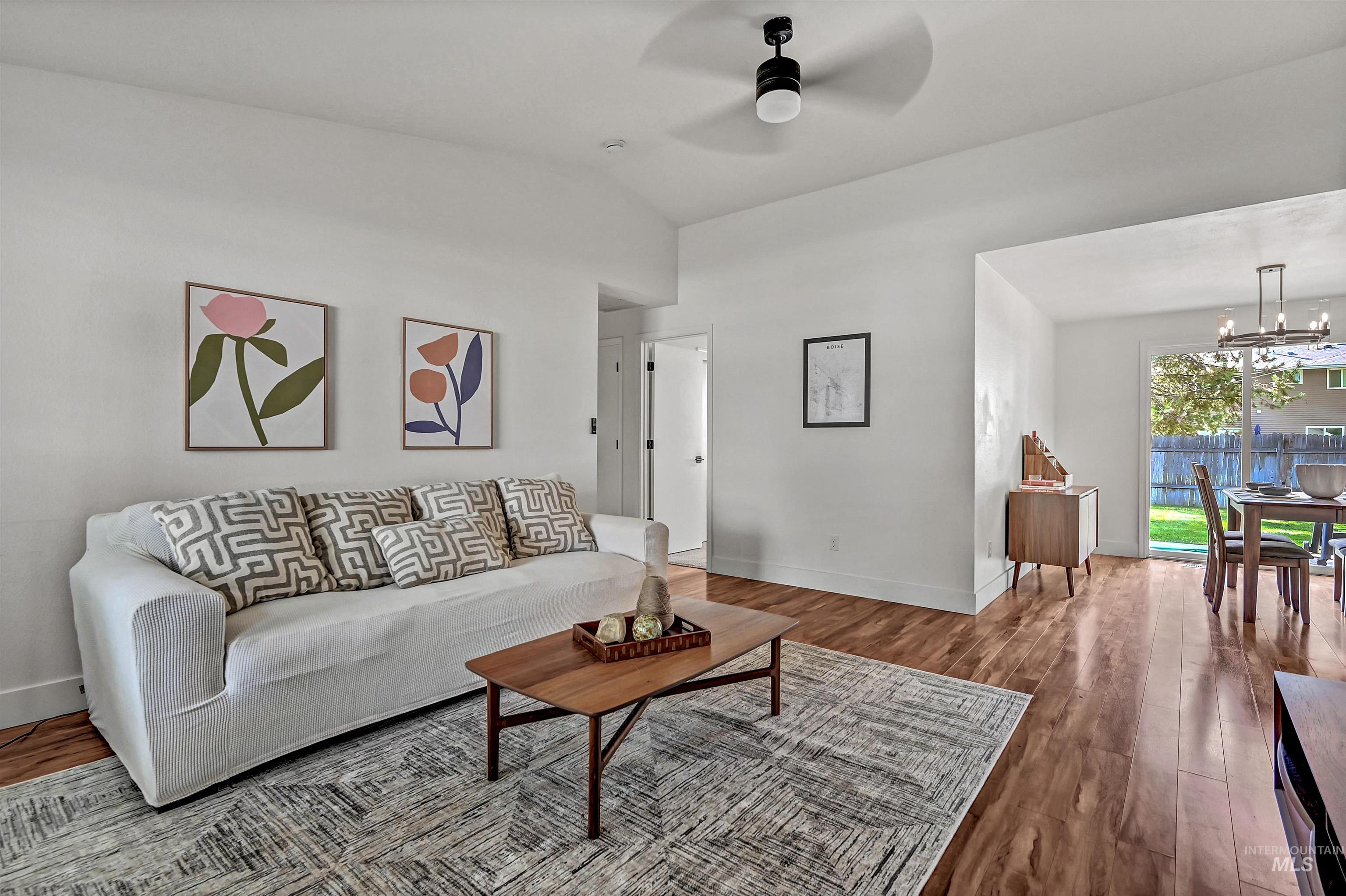 Living room featuring vaulted ceiling, wood-style floors, ceiling fan, and a chandelier