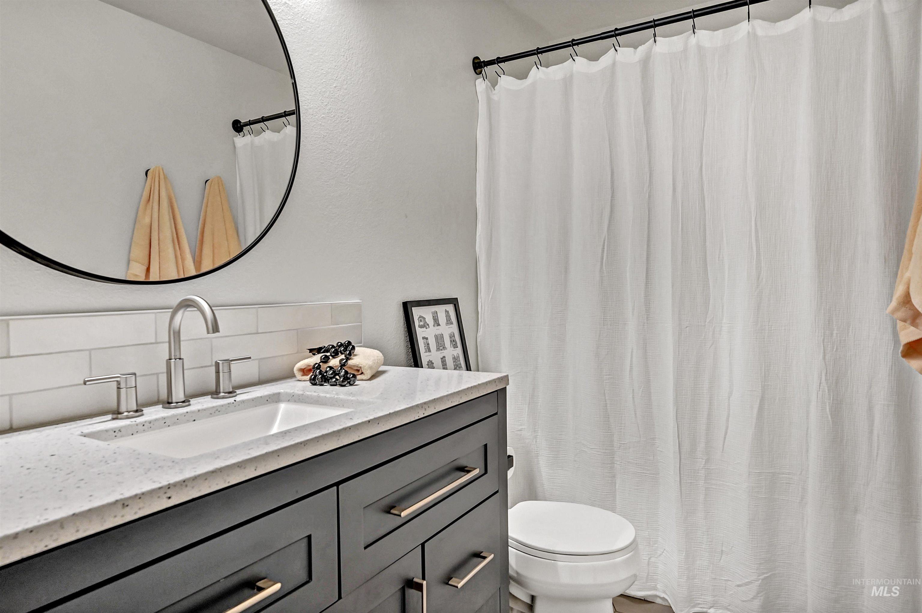 Full bathroom featuring vanity, tasteful backsplash, and curtained shower/tub combo