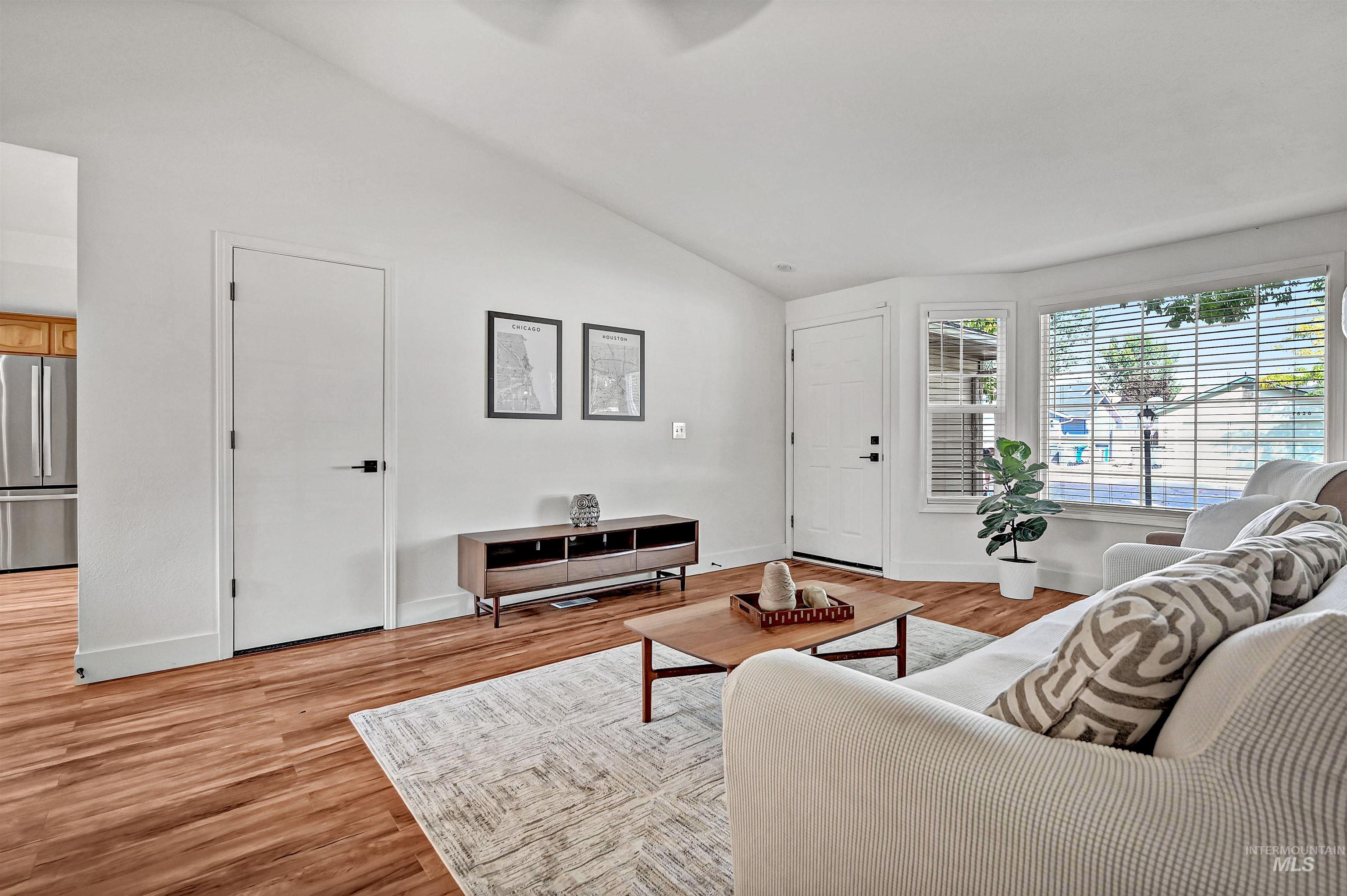 Living room featuring vaulted ceiling and light wood-style flooring