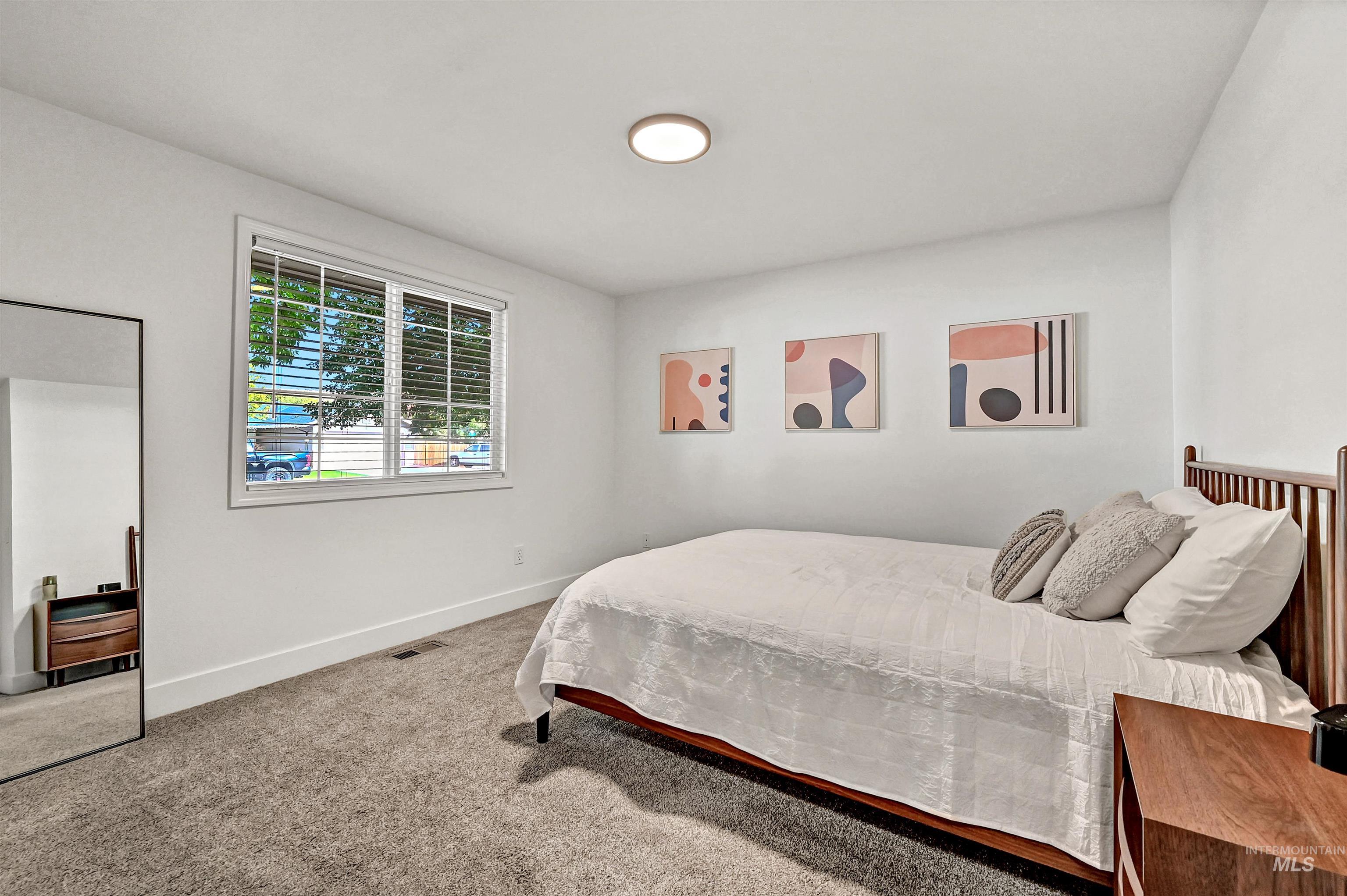 Primary ensuite with large windows, carpeting, & fresh paint