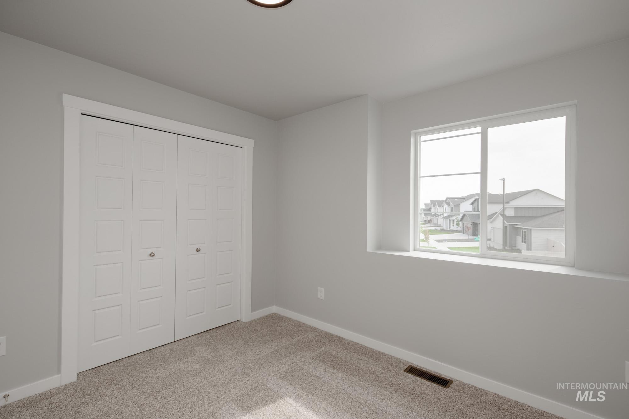 Unfurnished bedroom featuring light carpet and a closet