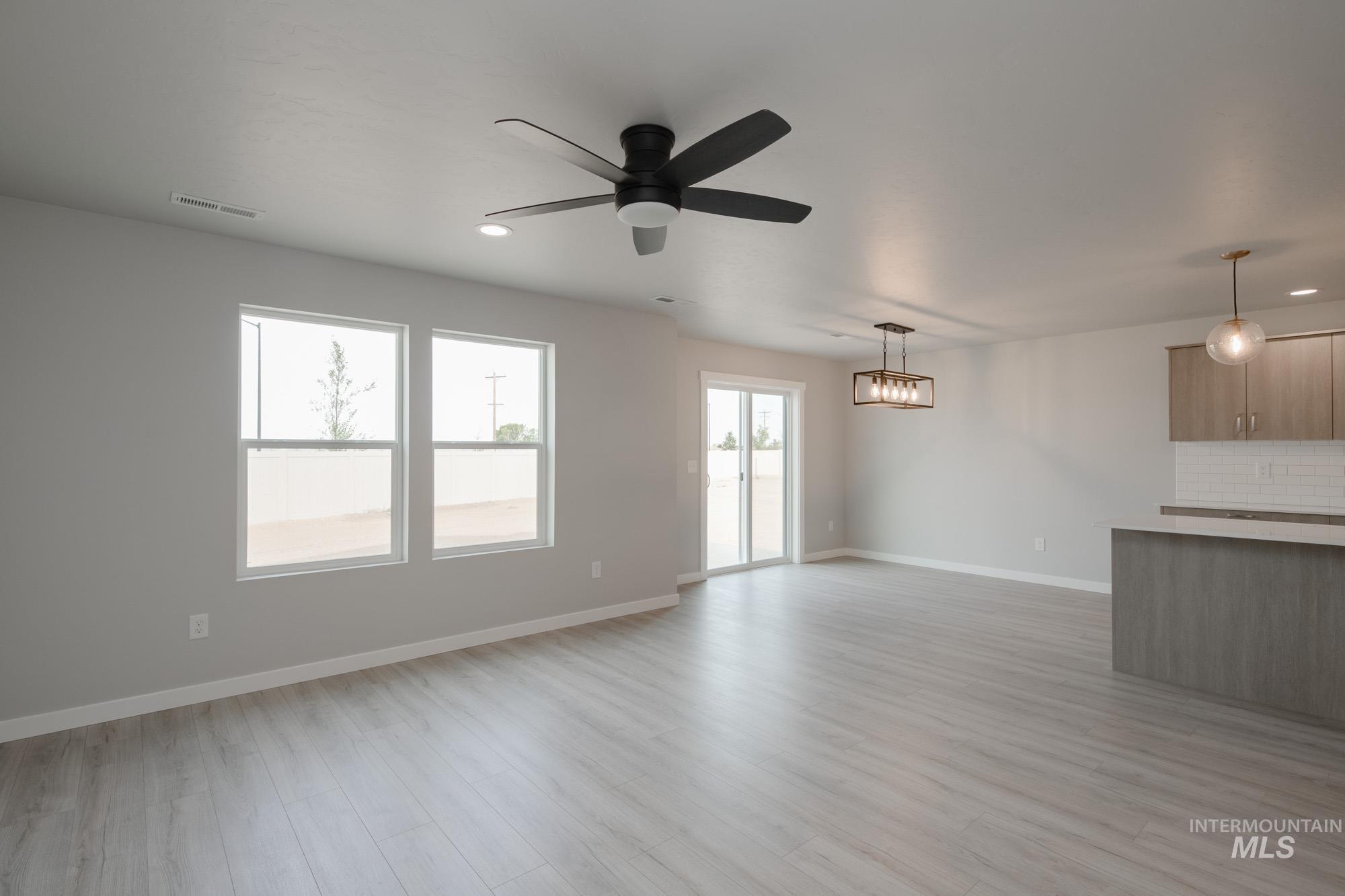Unfurnished living room featuring healthy amount of natural light, light wood finished floors, a ceiling fan, and recessed lighting