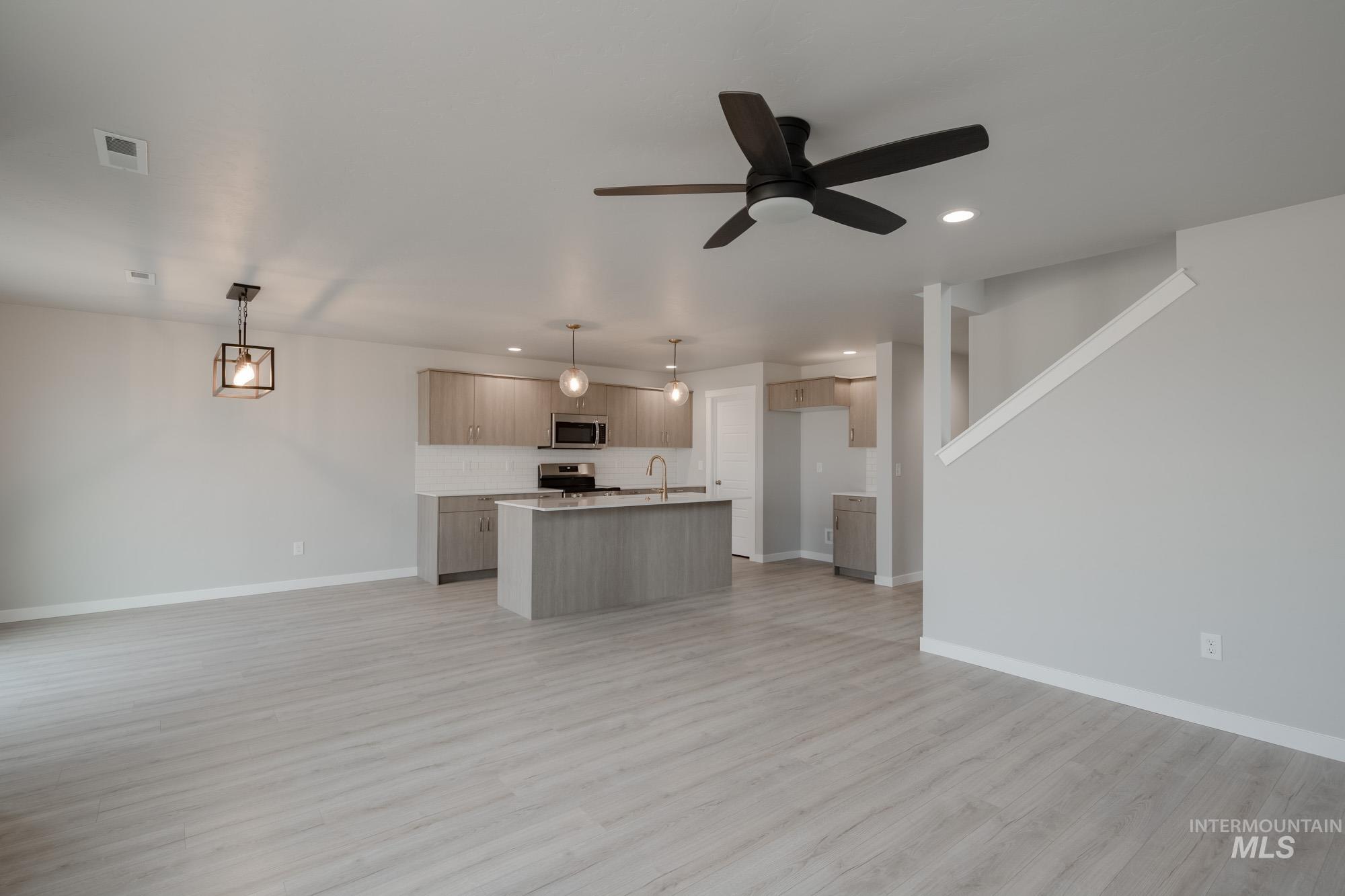 Unfurnished living room featuring light wood-type flooring, a ceiling fan, and recessed lighting