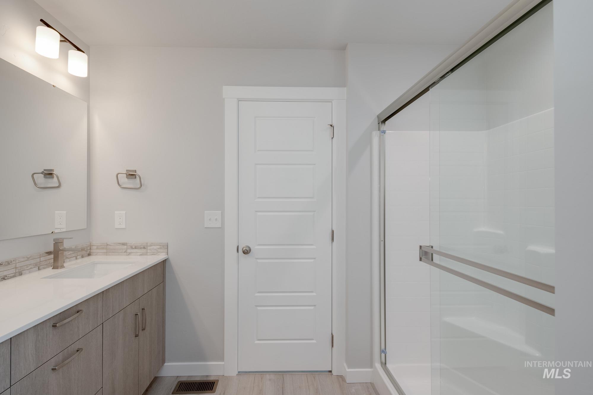 Full bathroom with vanity, a shower stall, and light wood-type flooring