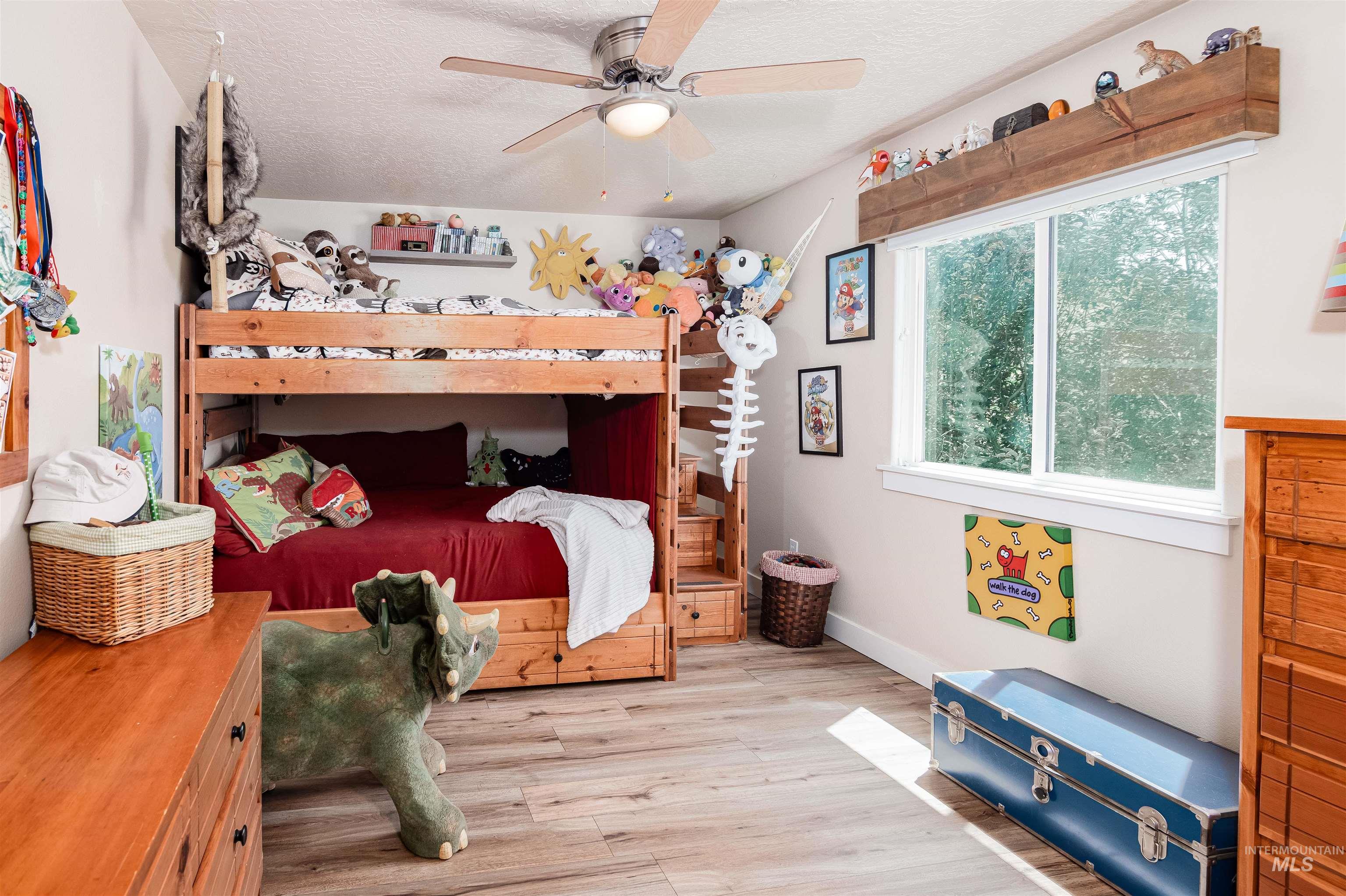 Room featuring wood-finish flooring, a double window with a wood valance, and a ceiling fan with light fixture