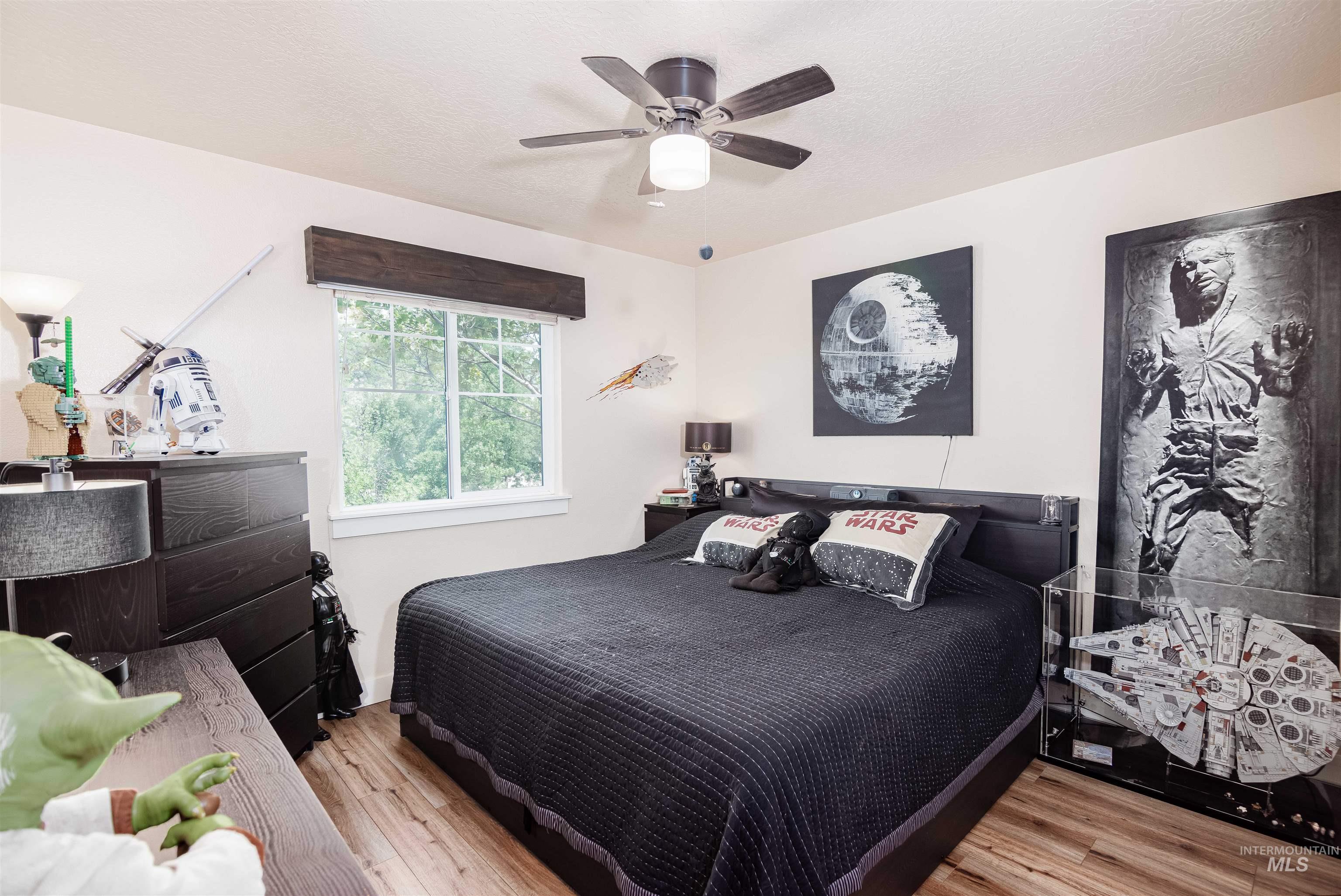 Bedroom featuring wood-finish flooring, a ceiling fan with integrated lighting, and a double-paned window