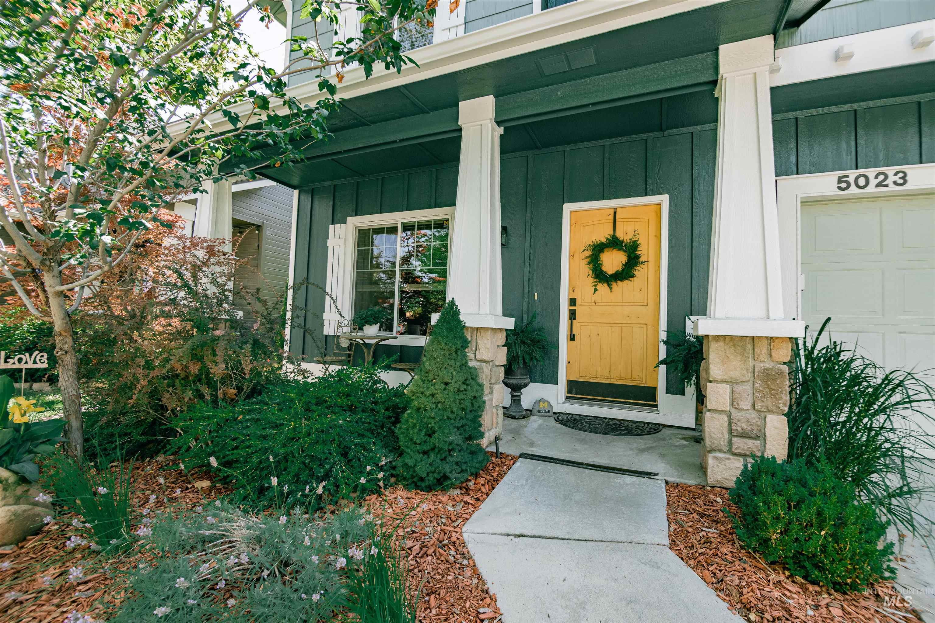 Front entry featuring a light wood door with dark hardware, framed by white columns with stone bases