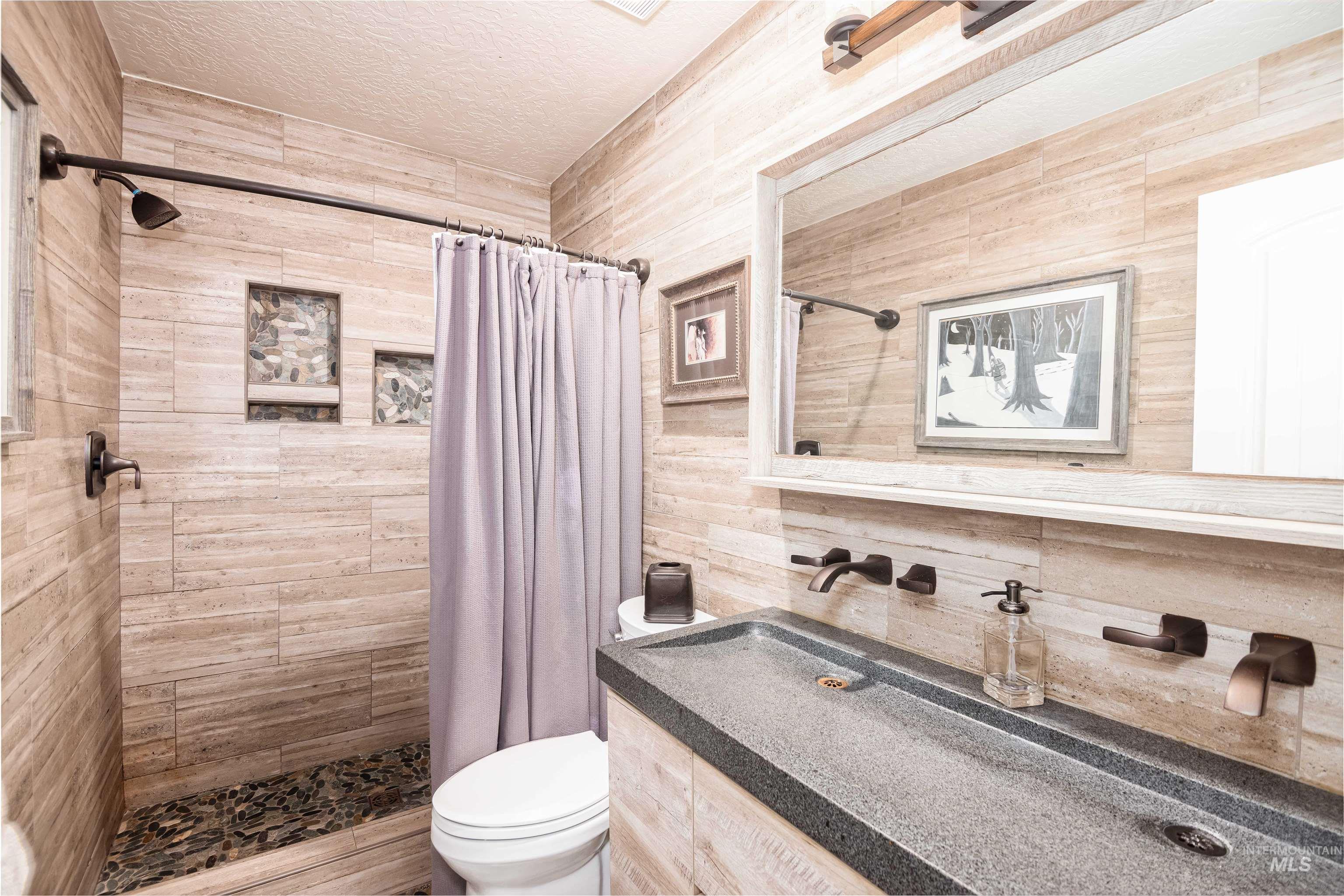 Bathroom featuring a walk-in shower with pebble tile floor and integrated shelving