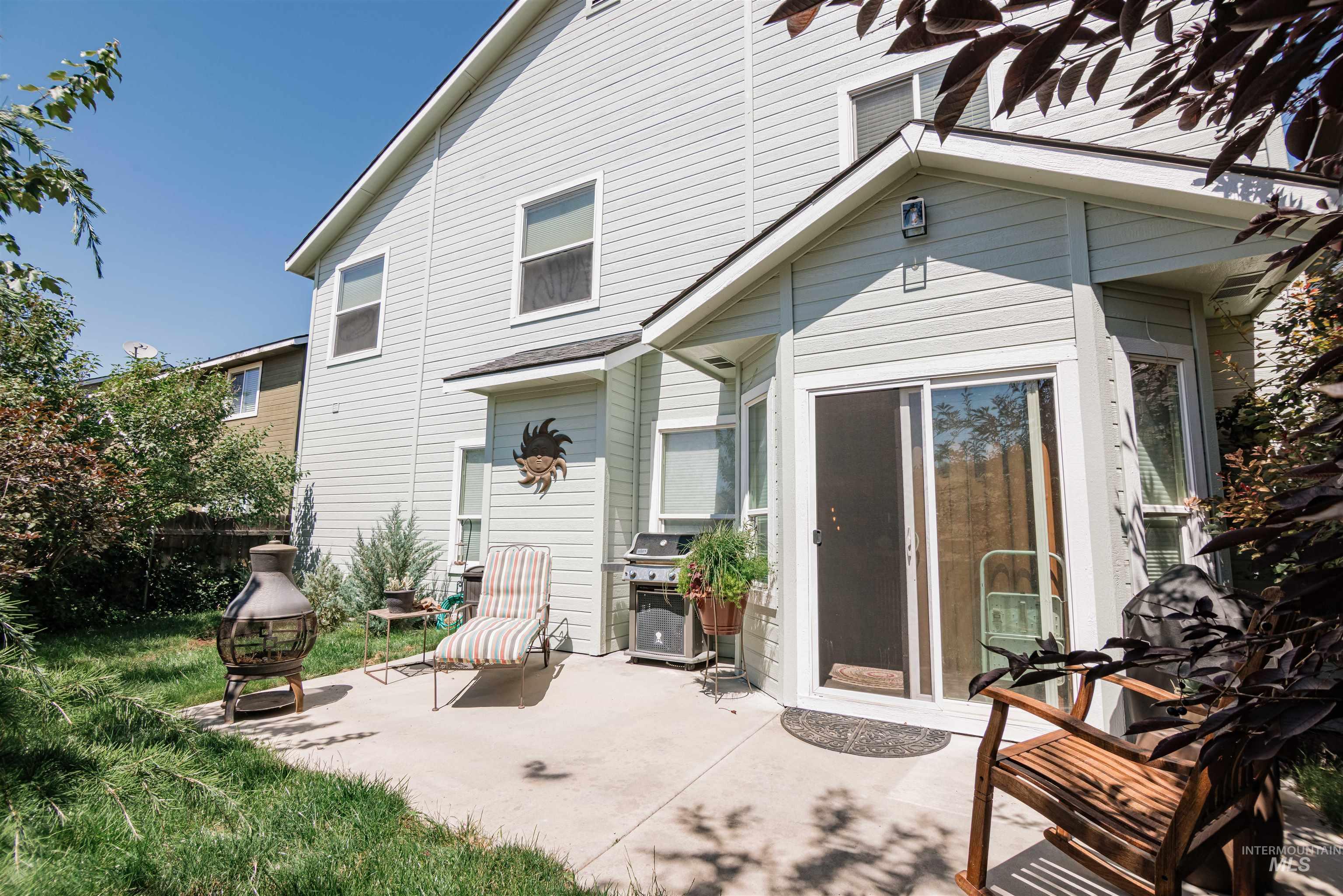 Rear exterior featuring light-colored siding, a concrete patio, and a sliding glass door