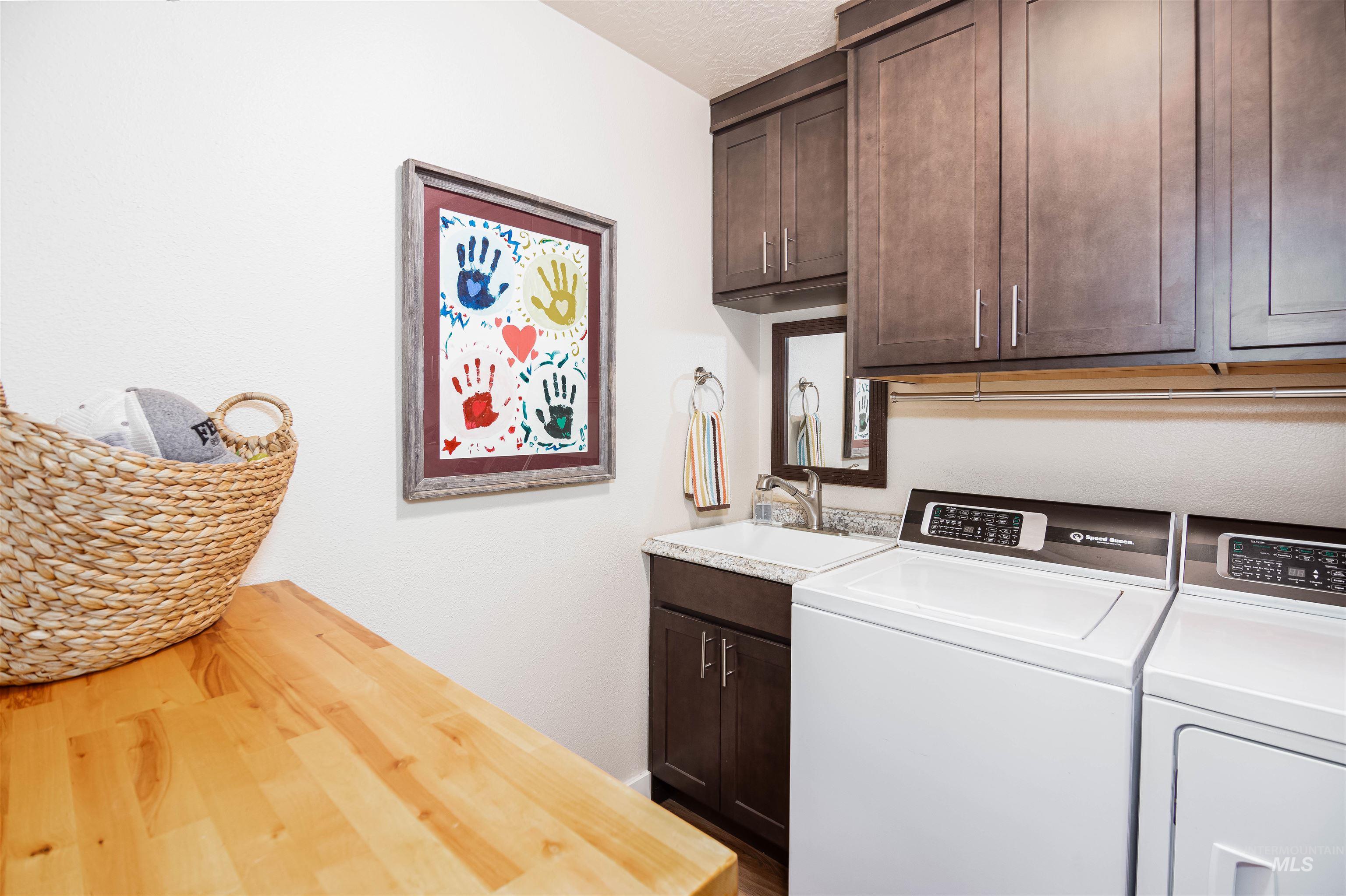 Laundry area featuring wood-finish countertops, dark wood cabinetry, and a sink with a custom backsplash