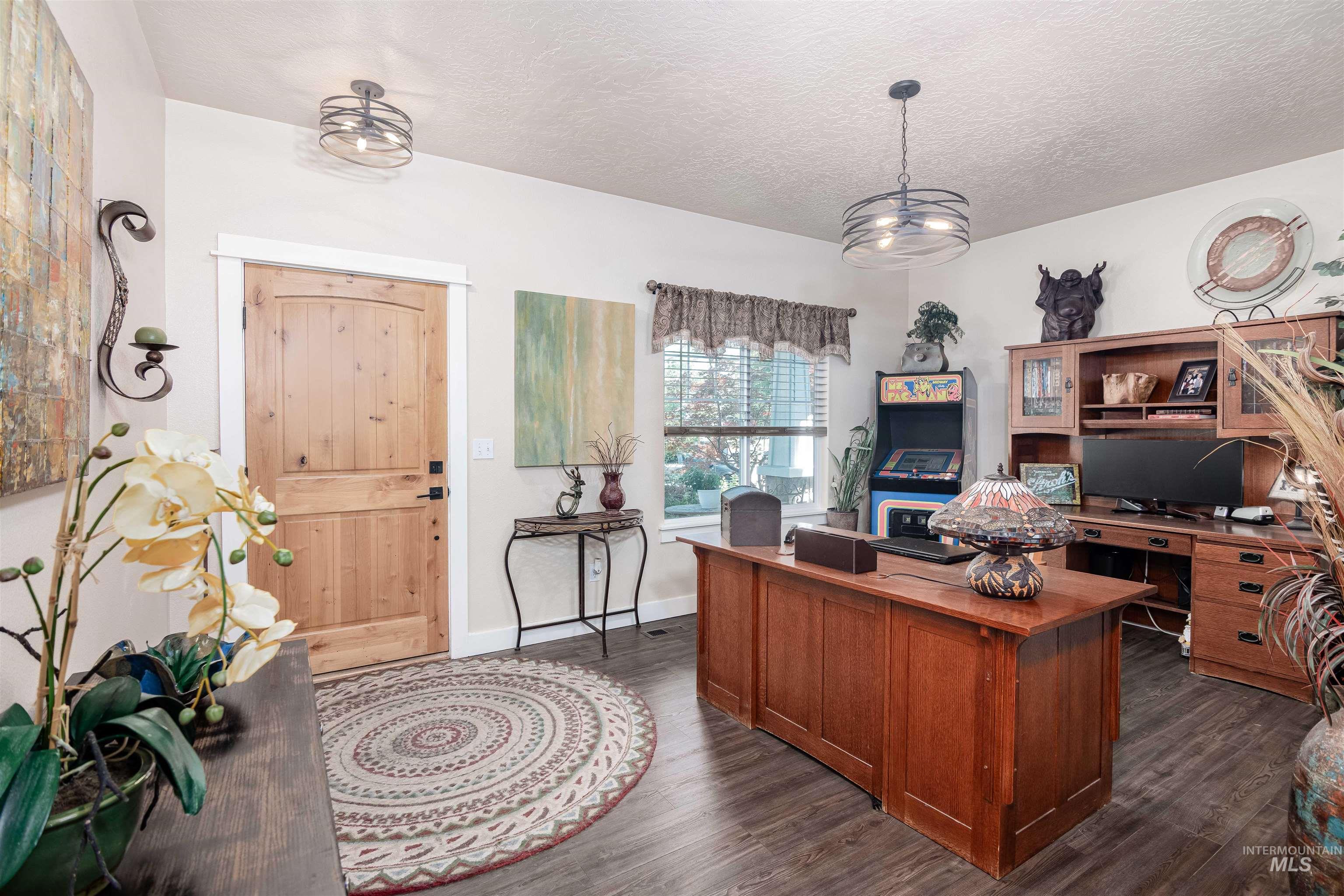 Entryway featuring a natural wood-finish door, dark wood-finish flooring, and white baseboards