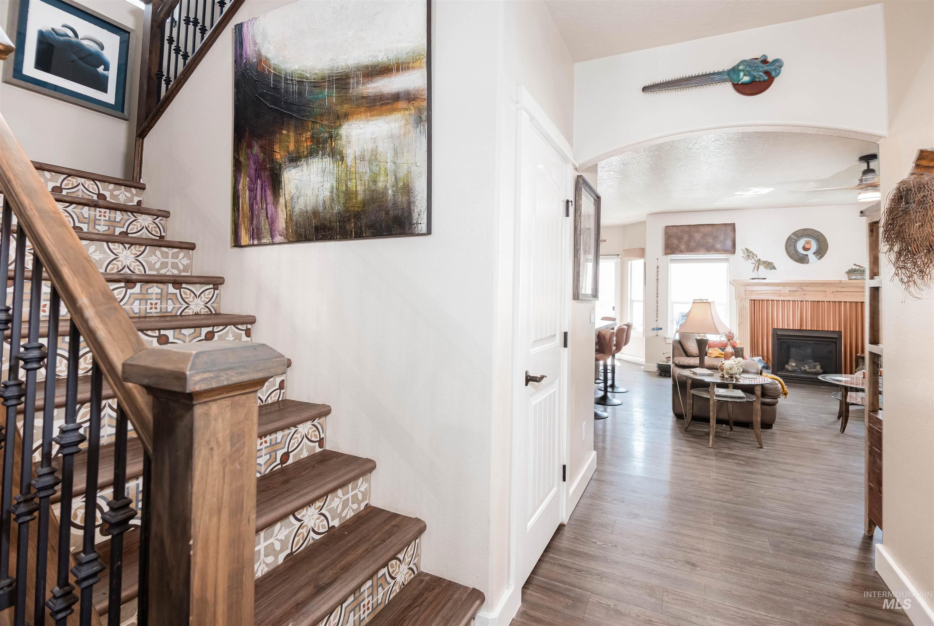 Entryway featuring a wood staircase with decorative risers and wrought iron balusters, tile risers.