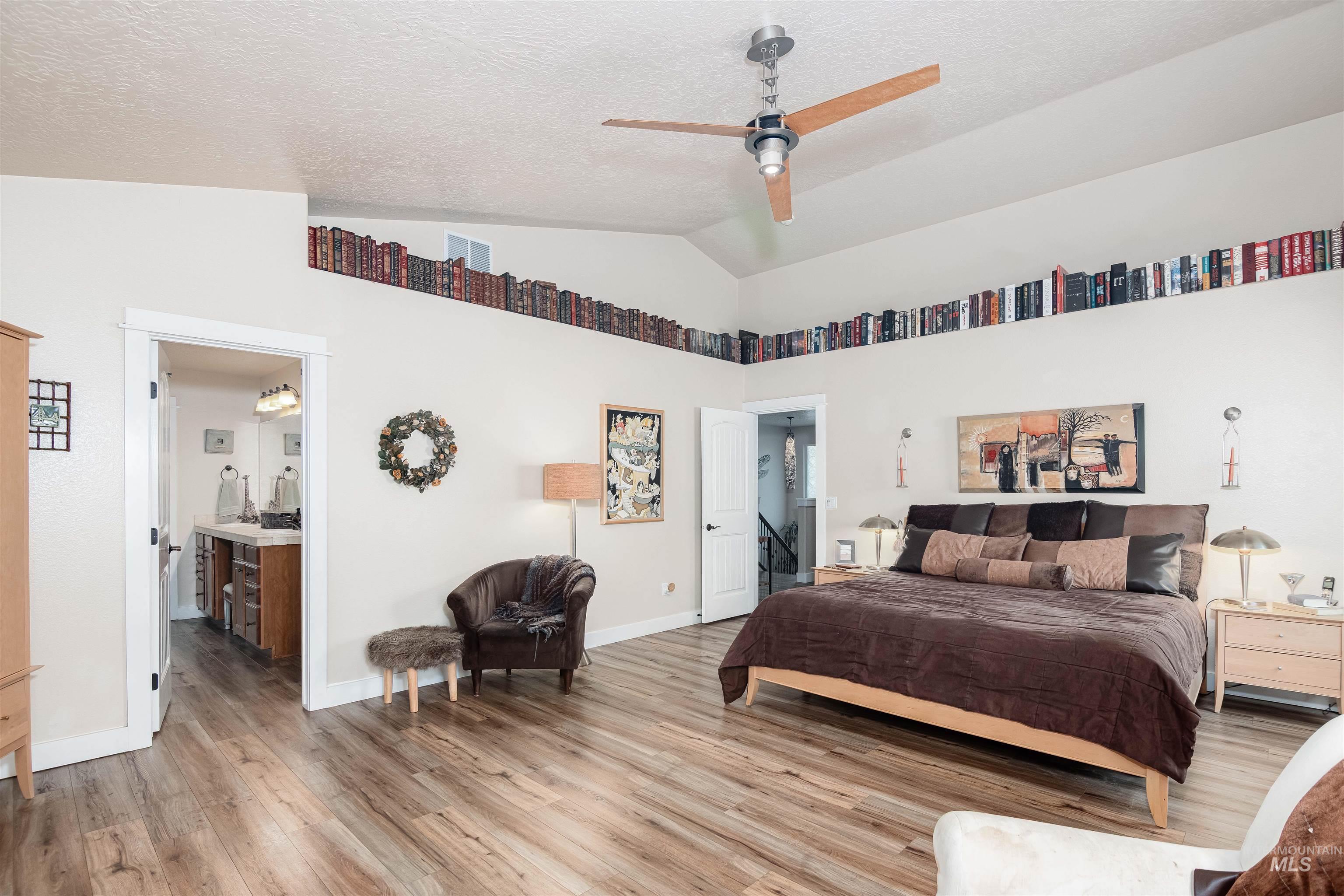 Spacious room featuring vaulted ceilings, wood-finish flooring, and an integrated ceiling fan