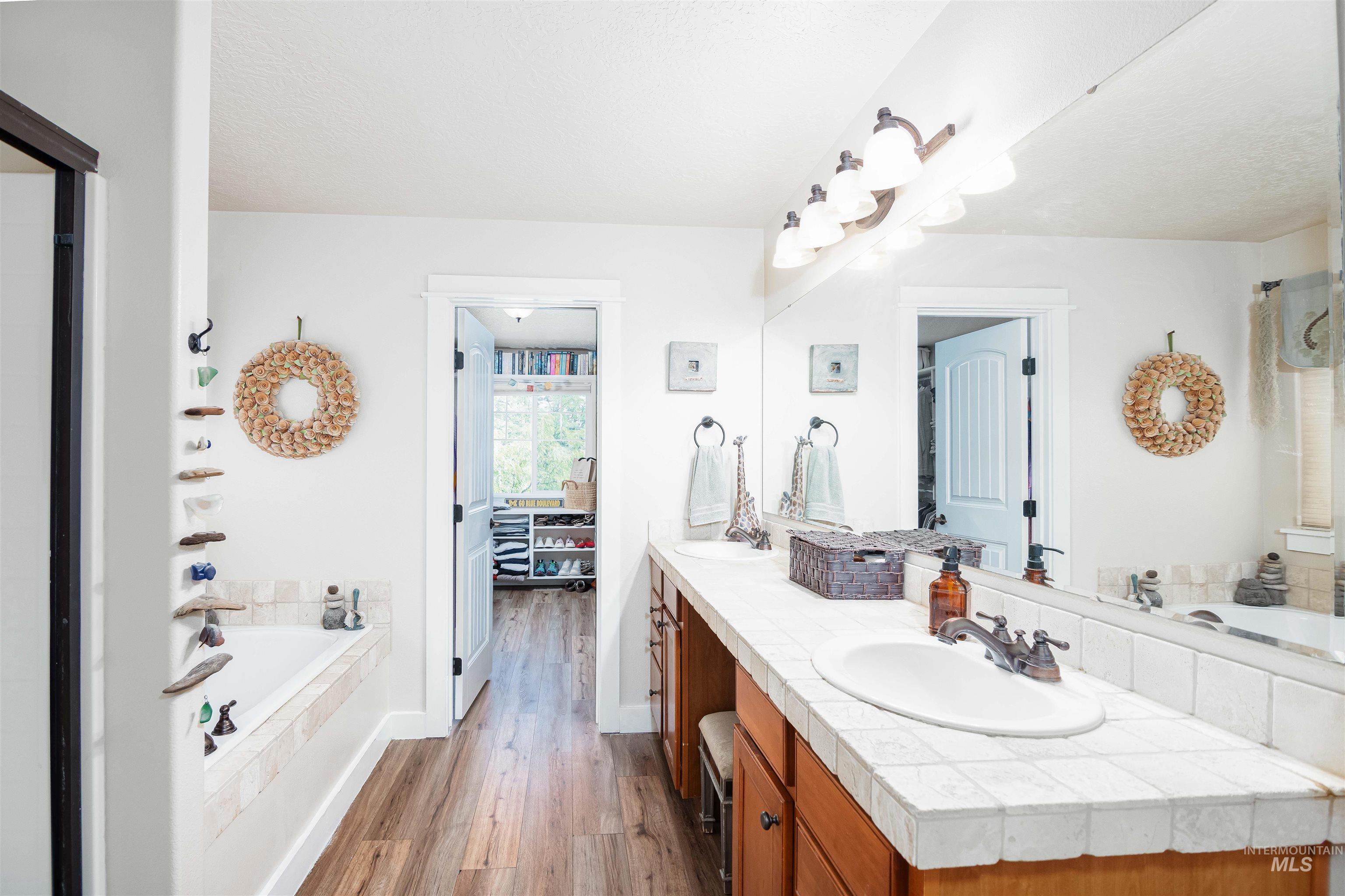 Double vanity with tile countertops and integrated sinks, shower and soaker tub.