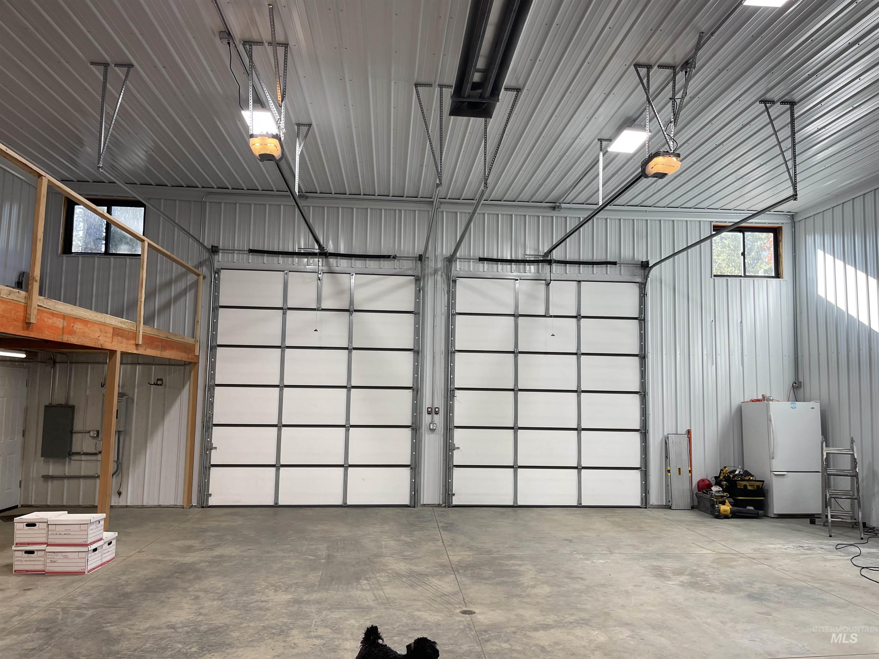Garage with metal wall, freestanding refrigerator, and electric panel