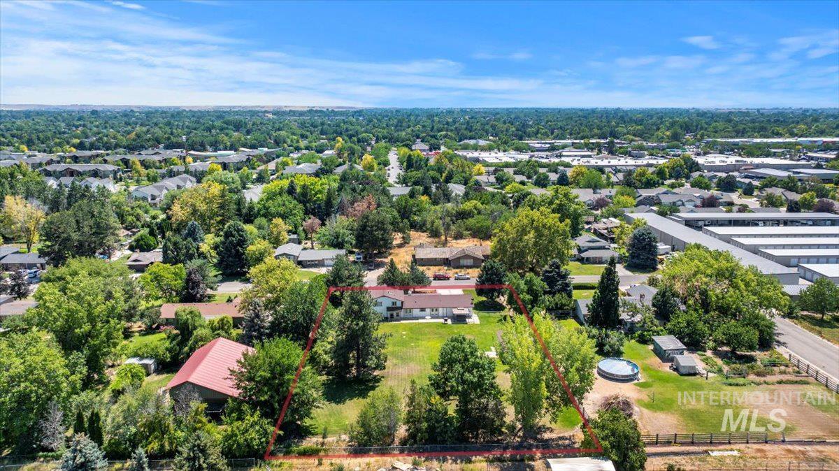 Aerial perspective of suburban area with property parcel outlined and a tree filled landscape