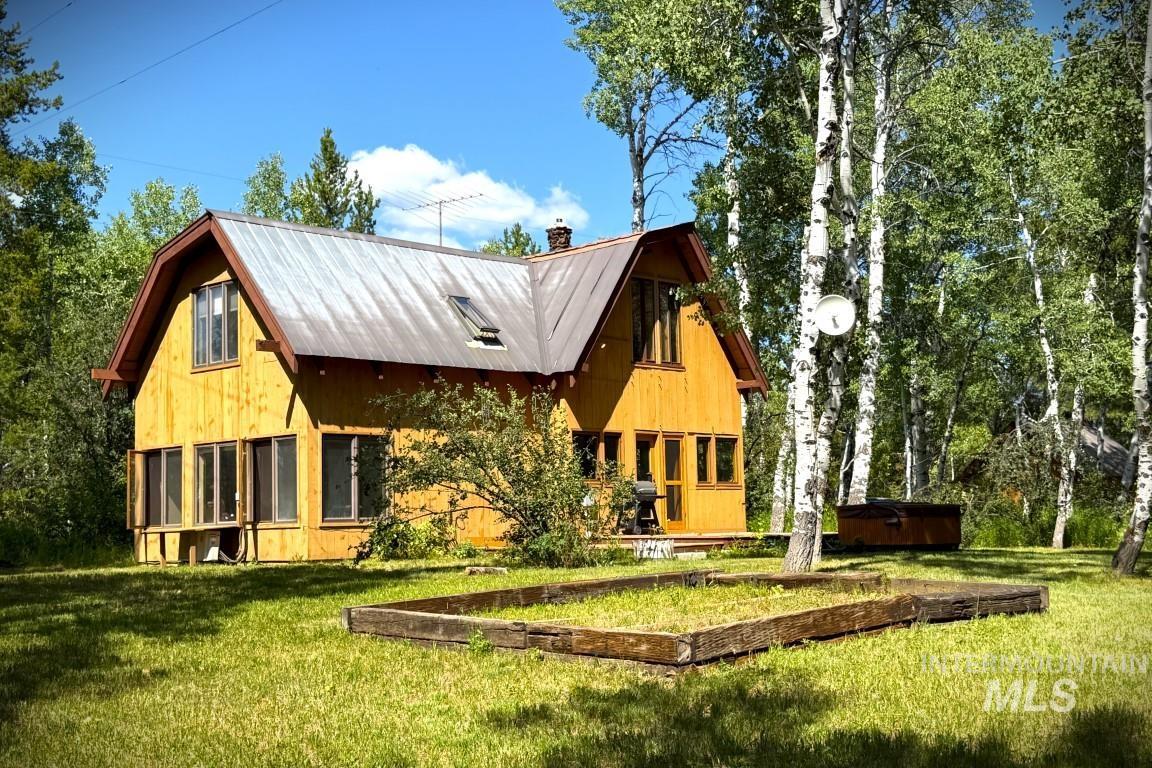 Rear view of property featuring a chimney, a lawn, and a metal roof