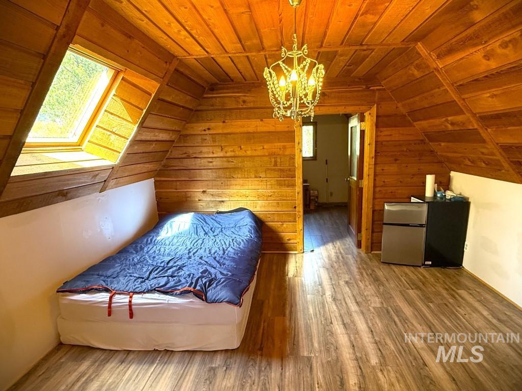 Bonus room with wood ceiling, a chandelier, wood finished floors, wooden walls, and lofted ceiling