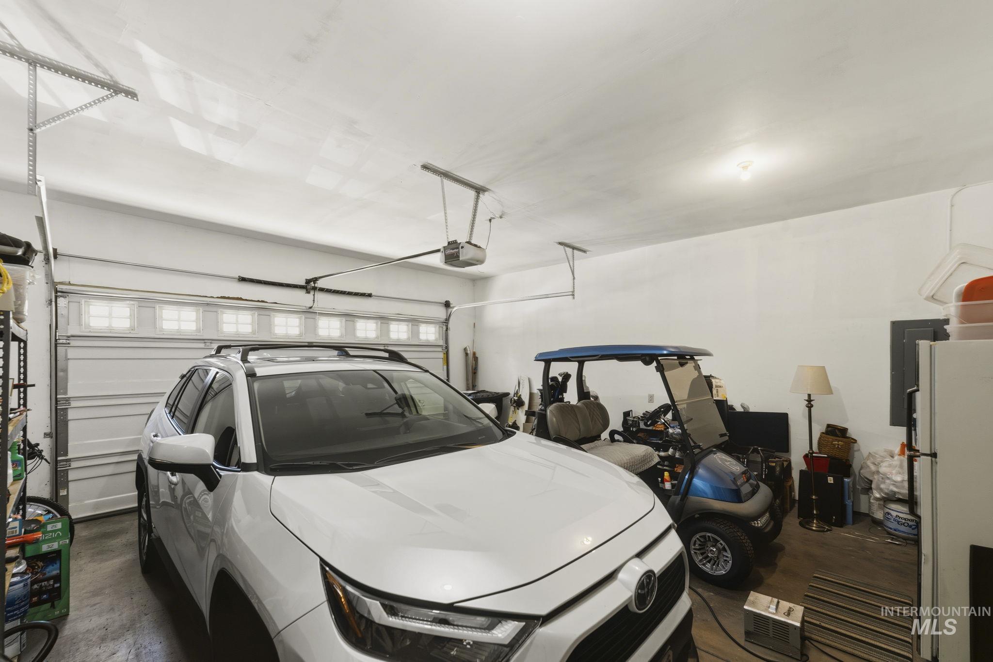 Spacious garage featuring a white overhead door with upper window panels, an automatic door opener, and concrete flooring
