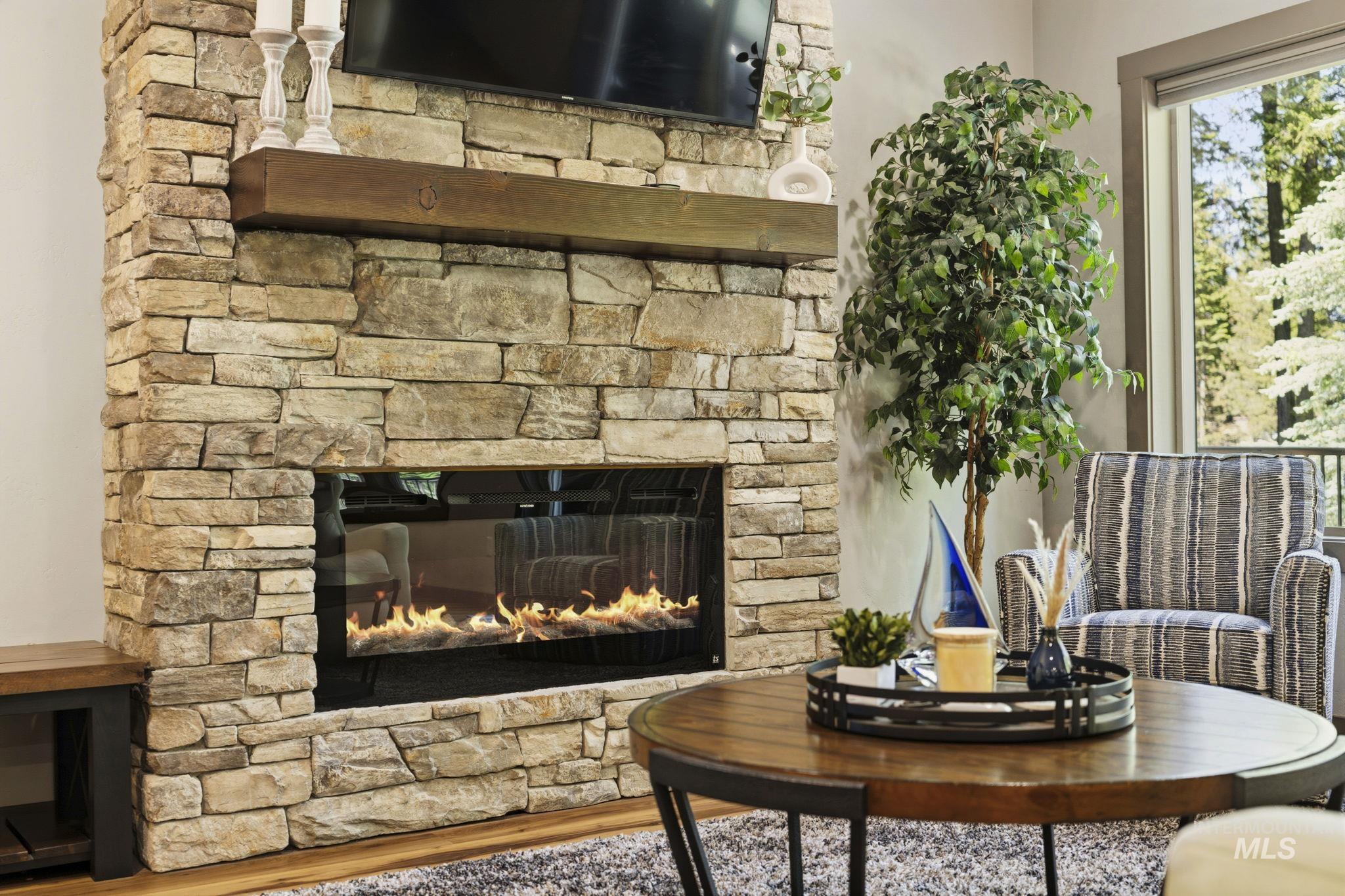 Stone-clad fireplace with a recessed linear gas insert and a rustic wood mantel