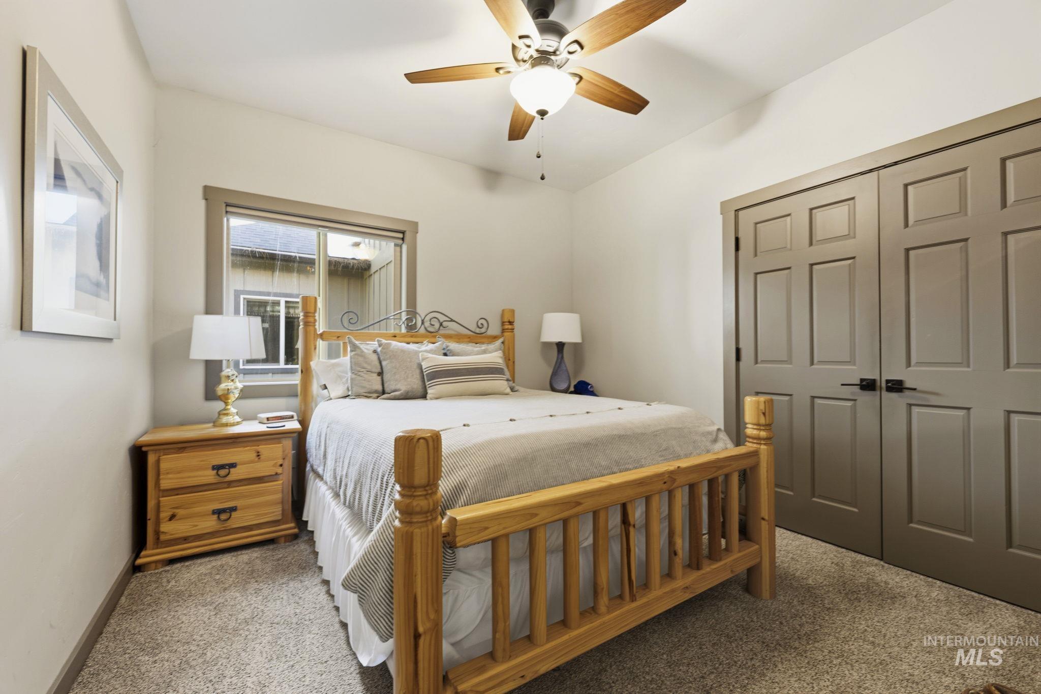 Carpeted room featuring a ceiling fan with integrated lighting, a window with dark trim, and paneled double doors