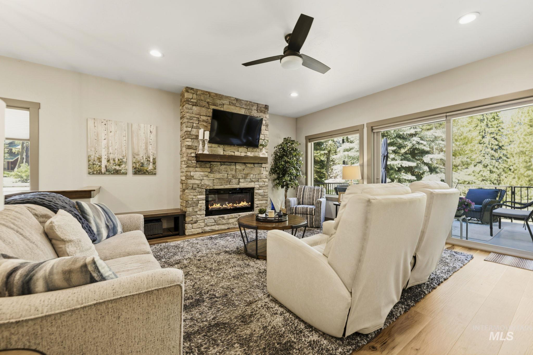 Living room featuring a stacked stone fireplace with a built-in electric insert and wood mantel, recessed lighting, and a ceiling fan