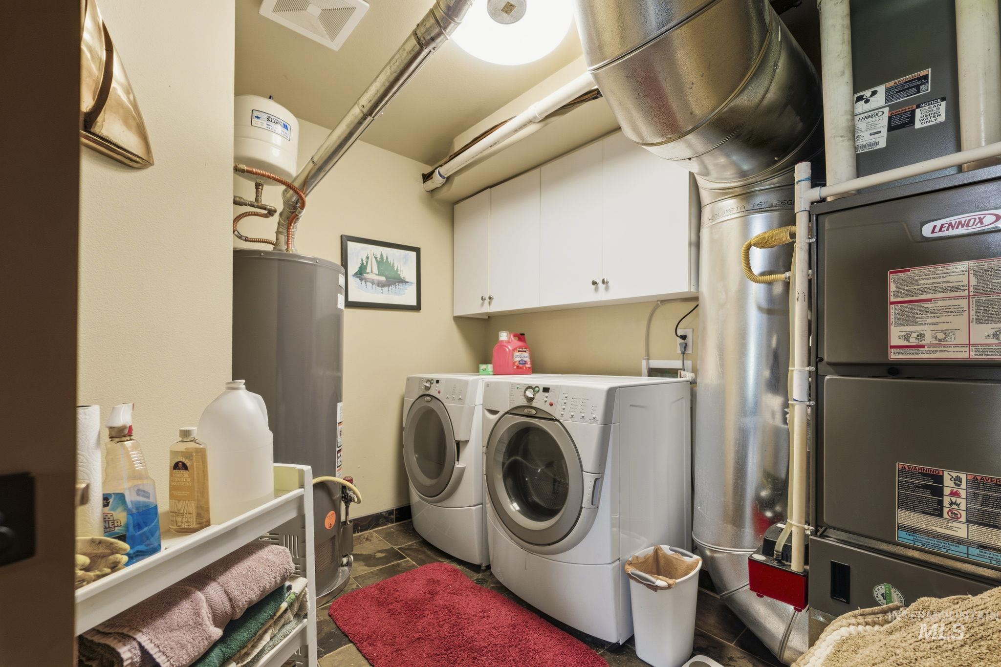 Dedicated utility area featuring a water heater, furnace system, and overhead cabinetry
