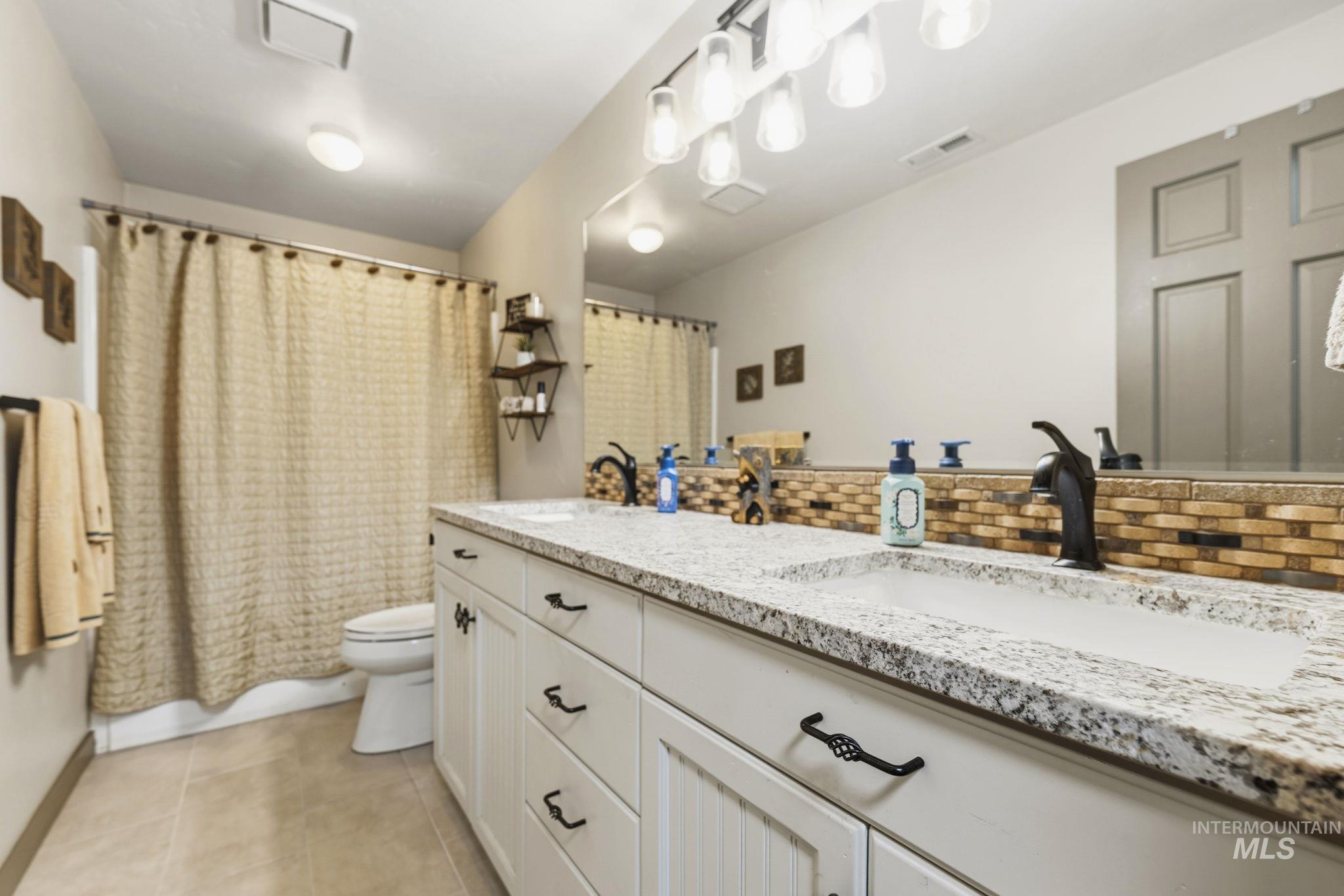 Dual vanity featuring integrated sinks, speckled countertops, and dark bronze fixtures